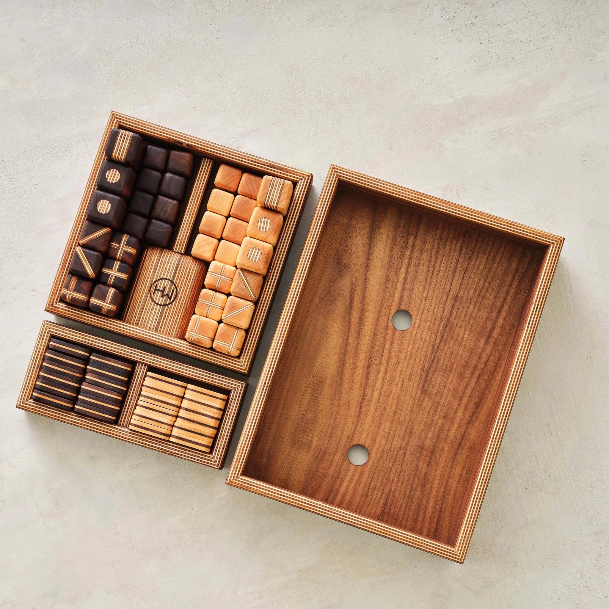 Overhead of walnut storage trays with sorted chess and checkers pieces beside empty box