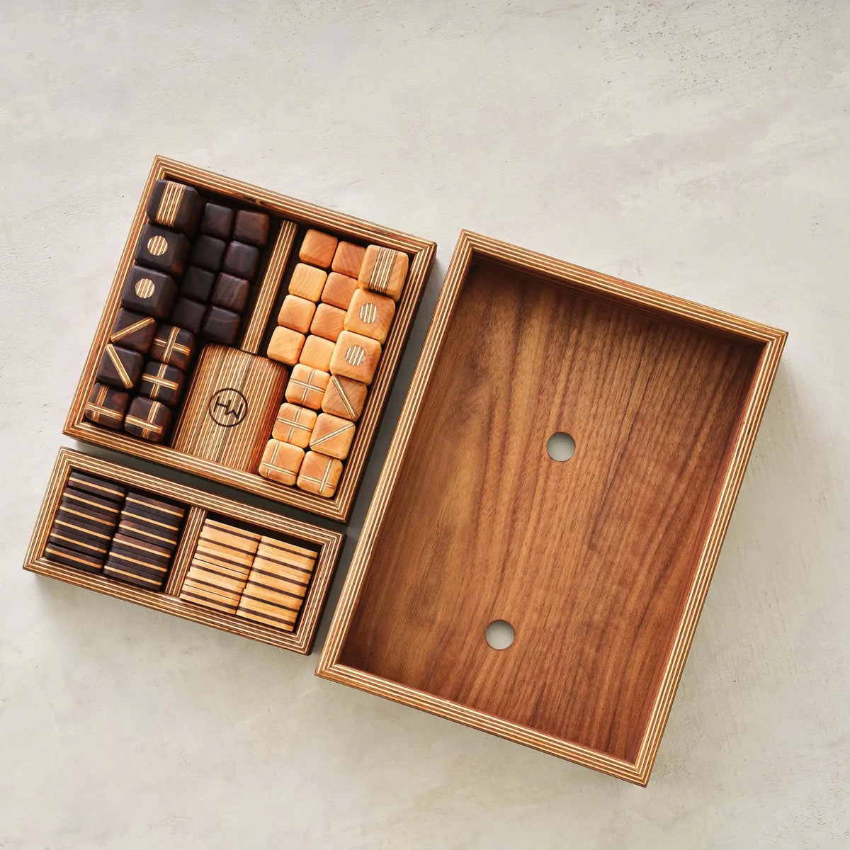 Overhead of walnut storage trays with sorted chess and checkers pieces beside empty box