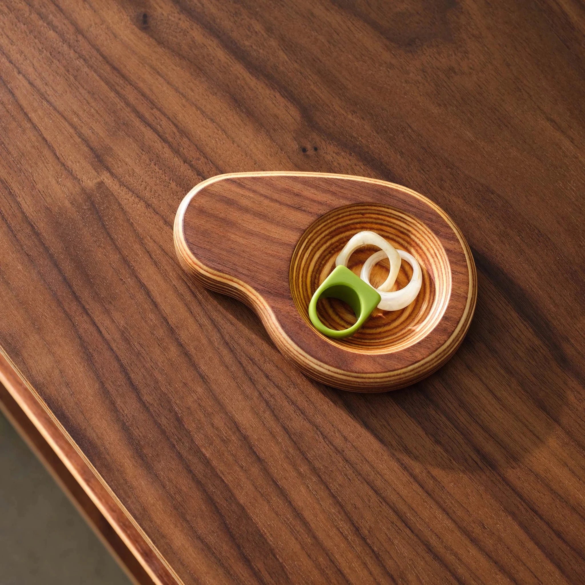 Walnut ring dish with green and white rings, staged on walnut tabletop