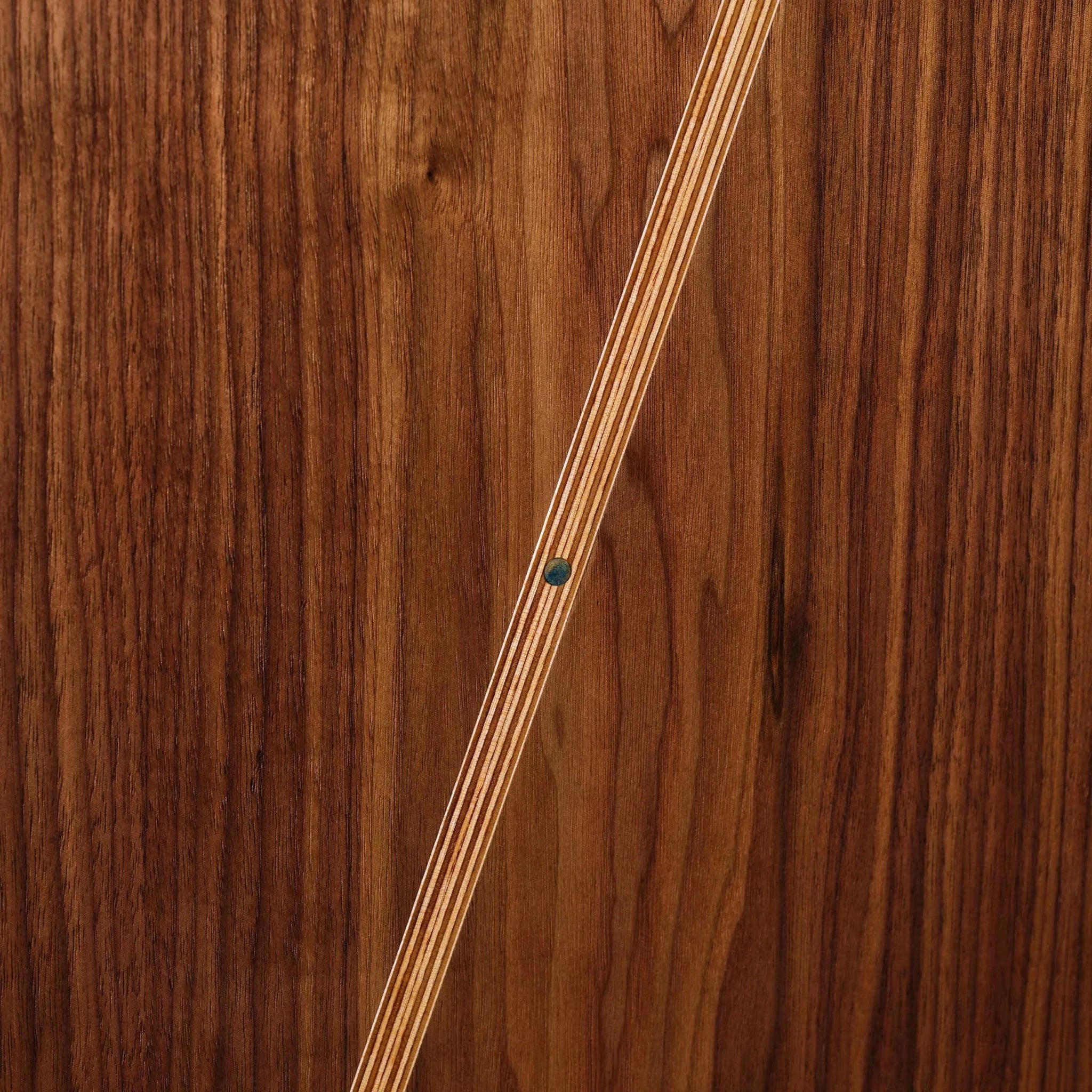 Closeup of walnut Sunbeam art with birch inlay stripe and turquoise dot