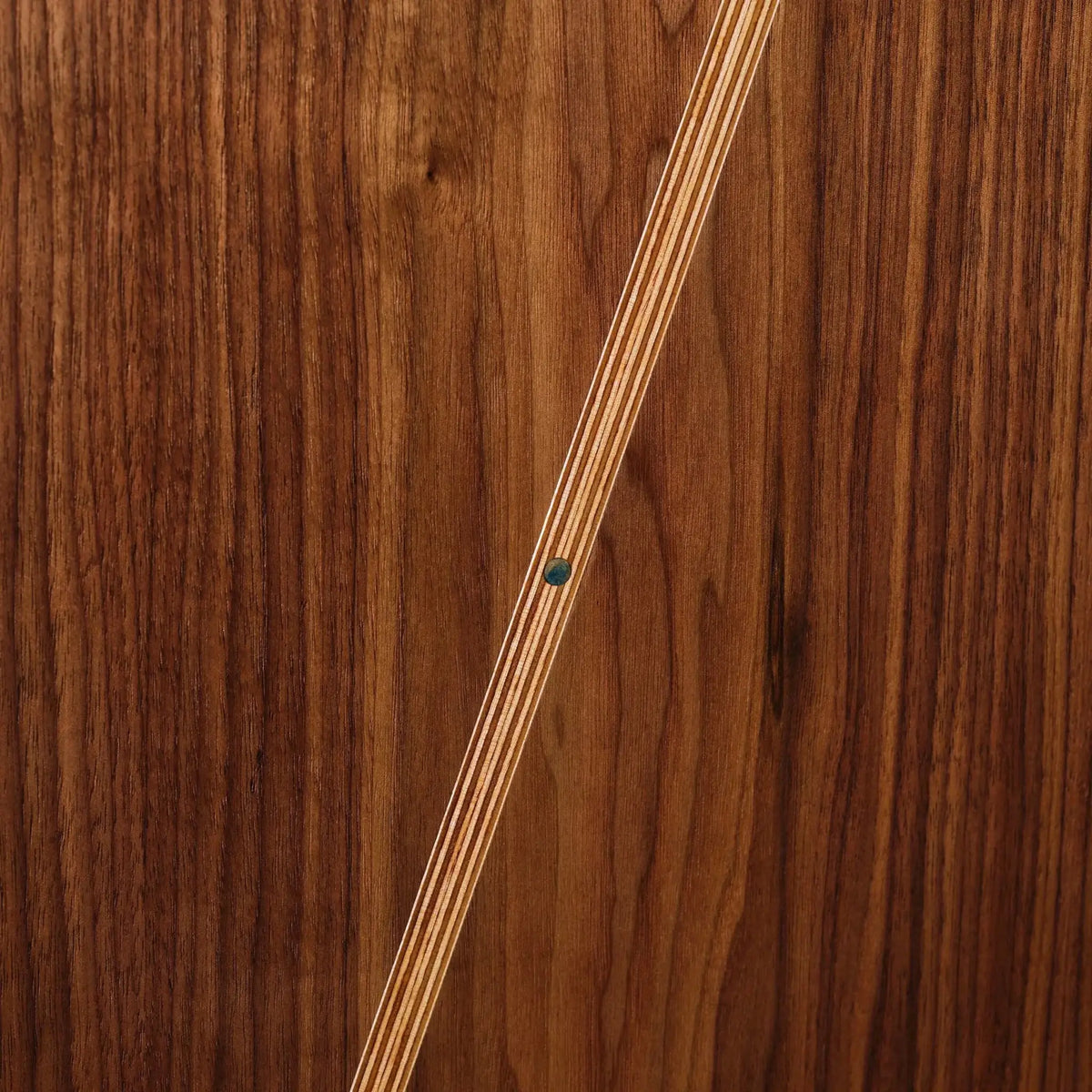 Closeup of walnut Sunbeam art with birch inlay stripe and turquoise dot