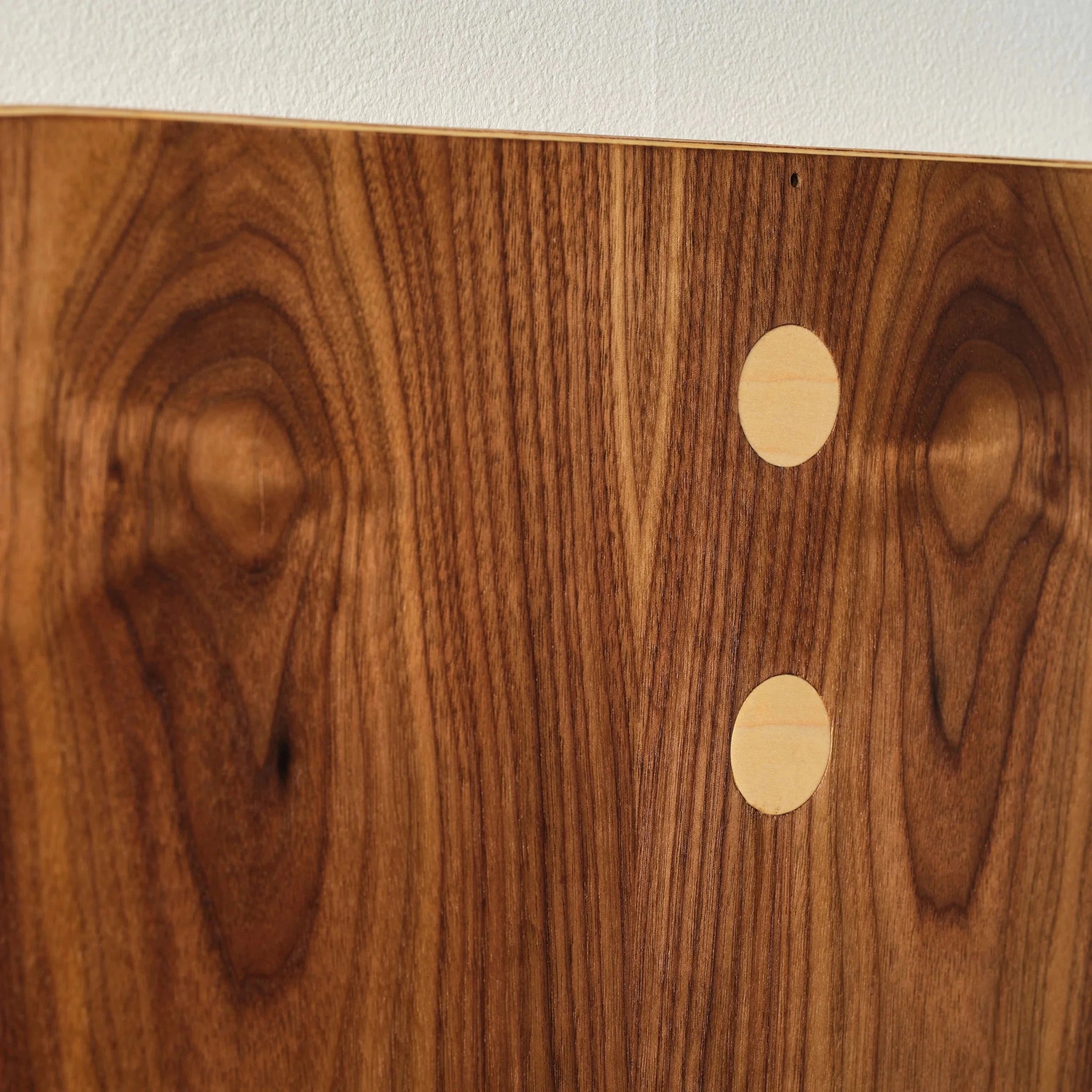 Closeup of walnut System panel showing two oval maple dot inlays