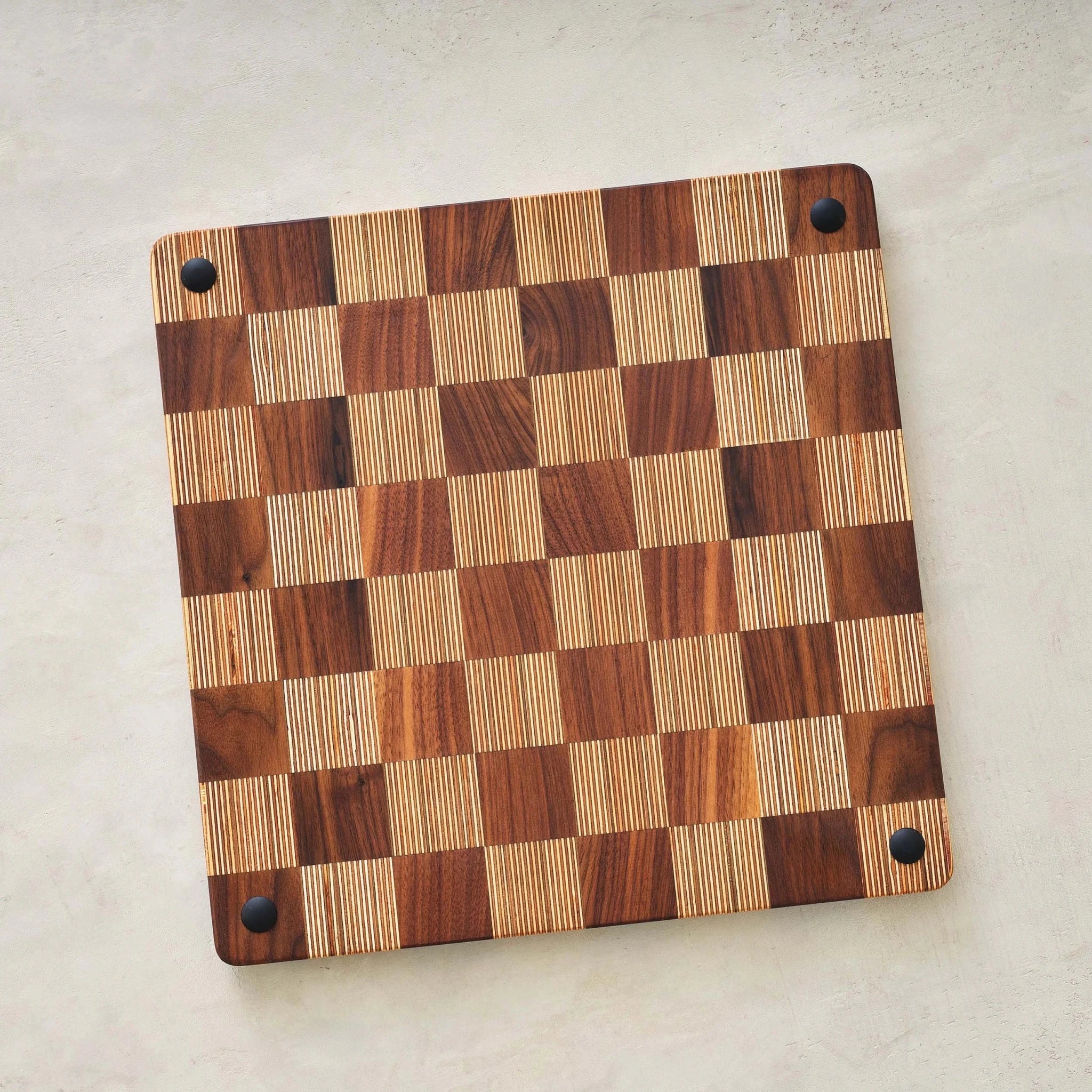 Underside of end-grain checkerboard game board showing black rubber corner feet