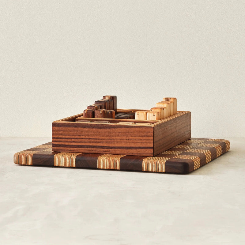 Walnut storage box holding game pieces atop striped end-grain board, front view