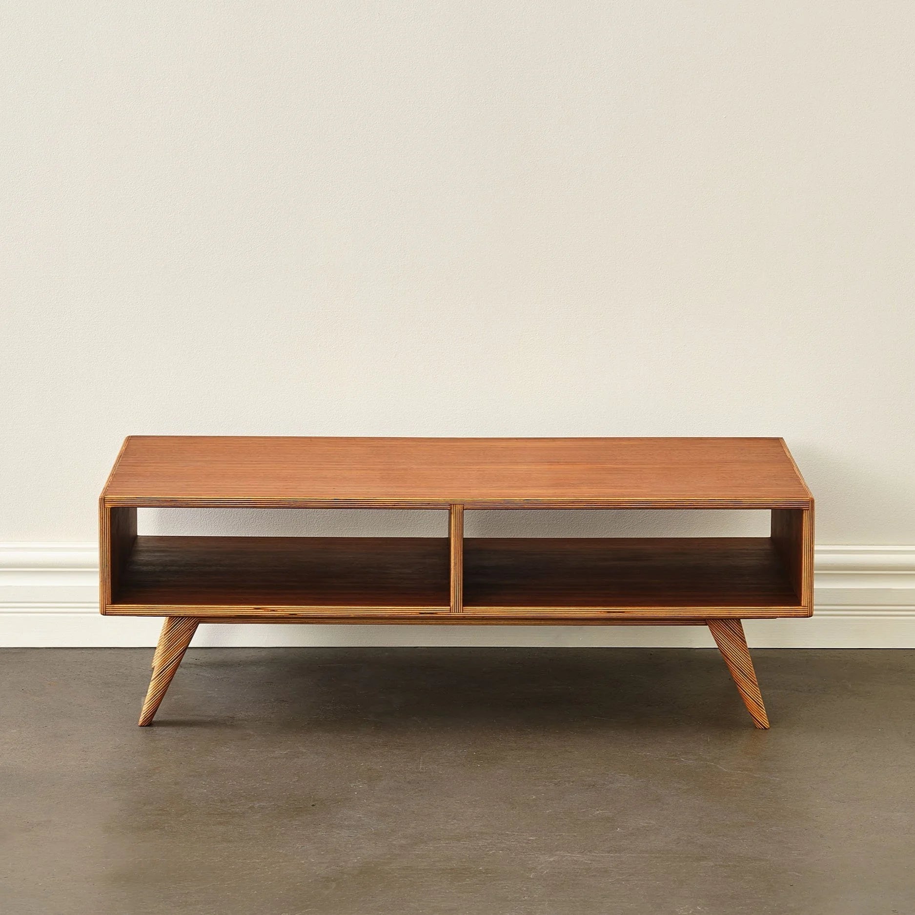 Walnut Coffee Table front view, open shelf, splayed plywood legs, empty, concrete floor