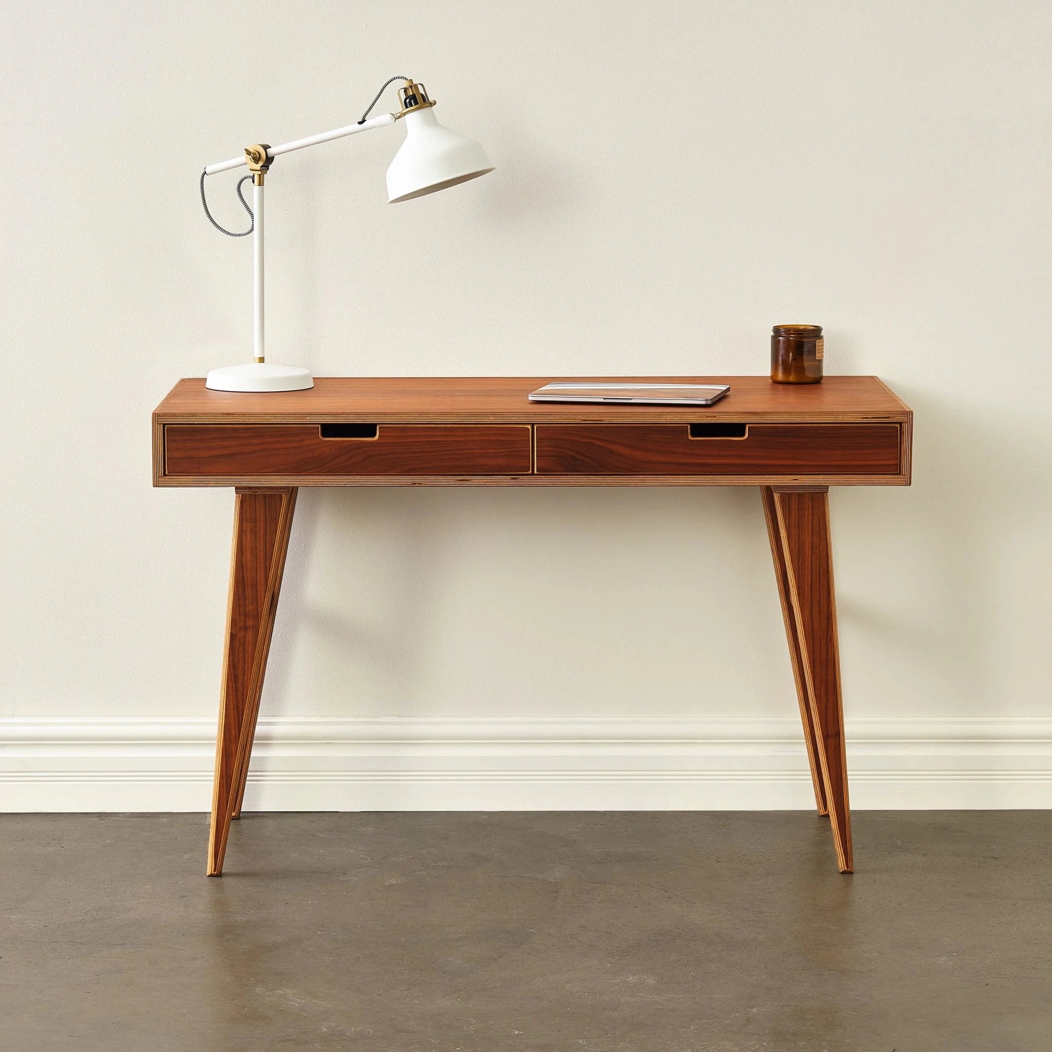 Styled walnut writing desk with white lamp, laptop and amber candle jar
