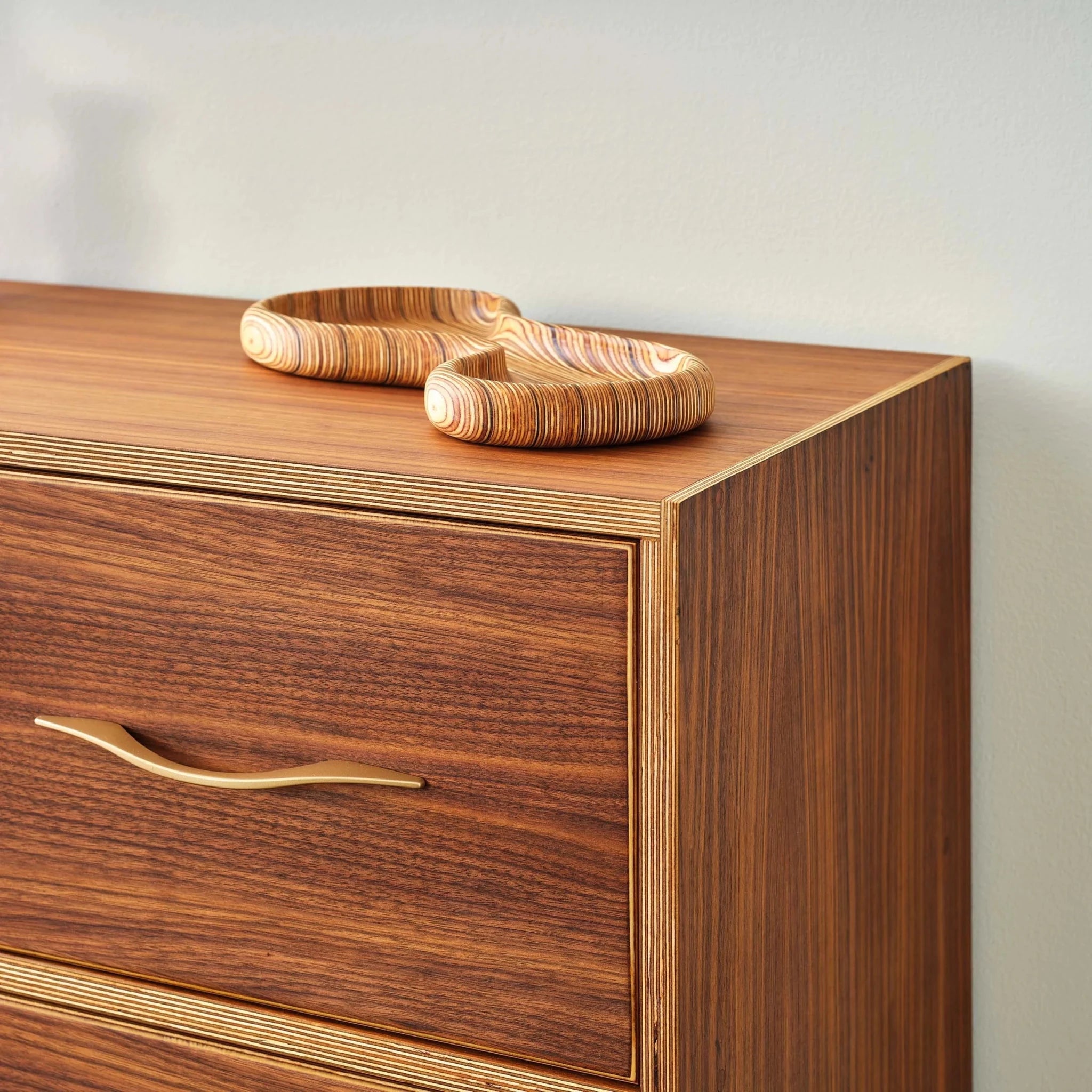 Close-up of walnut dresser top corner with birch plywood edge and wooden tray