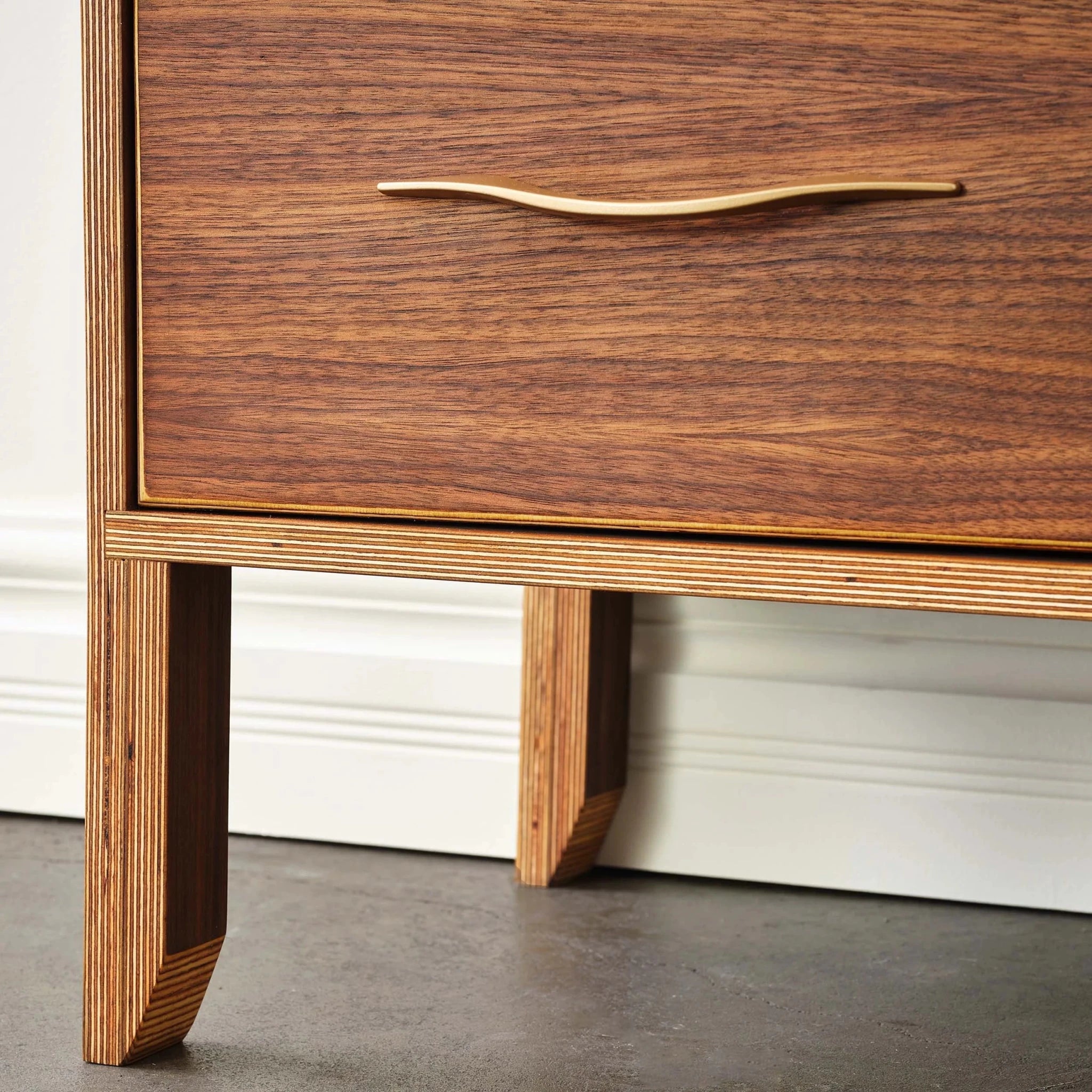Close-up walnut dresser leg detail, brass handle and layered birch plywood legs