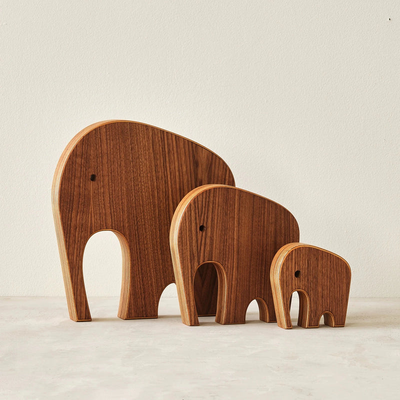 Three graduated walnut elephant sculptures, front view, layered birch edges, white background