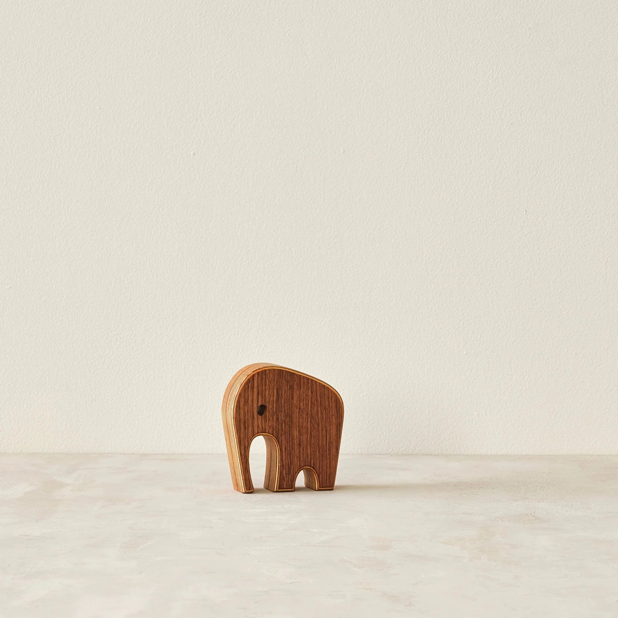 Small walnut elephant sculpture alone, front view, layered birch edge, neutral background