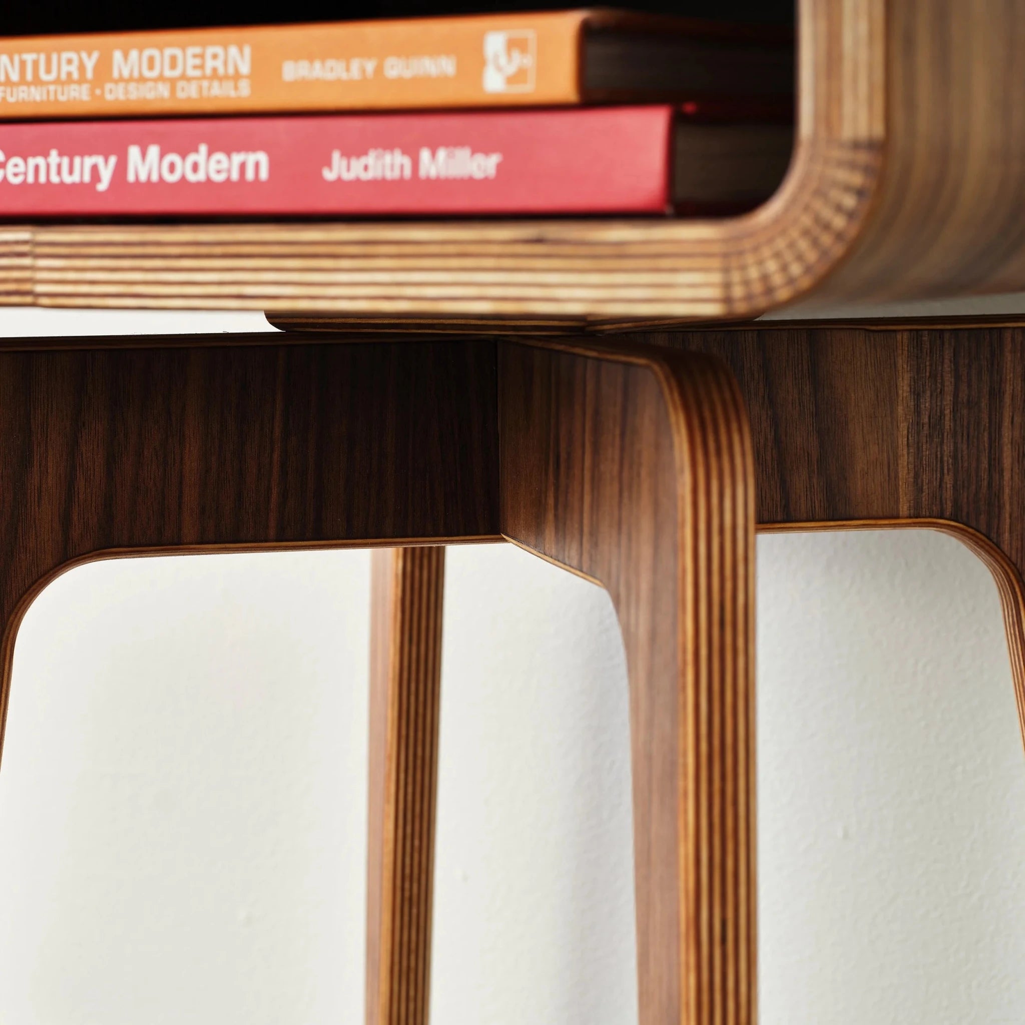 Detail of end table leg joinery and cubby with stacked mid-century modern books