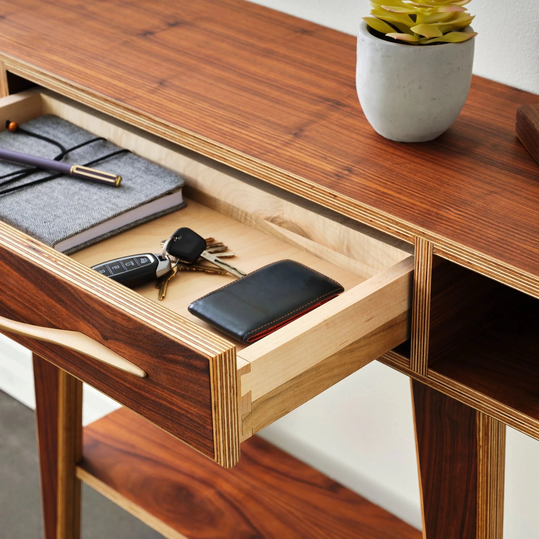 Walnut entry table with open drawer revealing keys, wallet, notebook; succulent pot on top