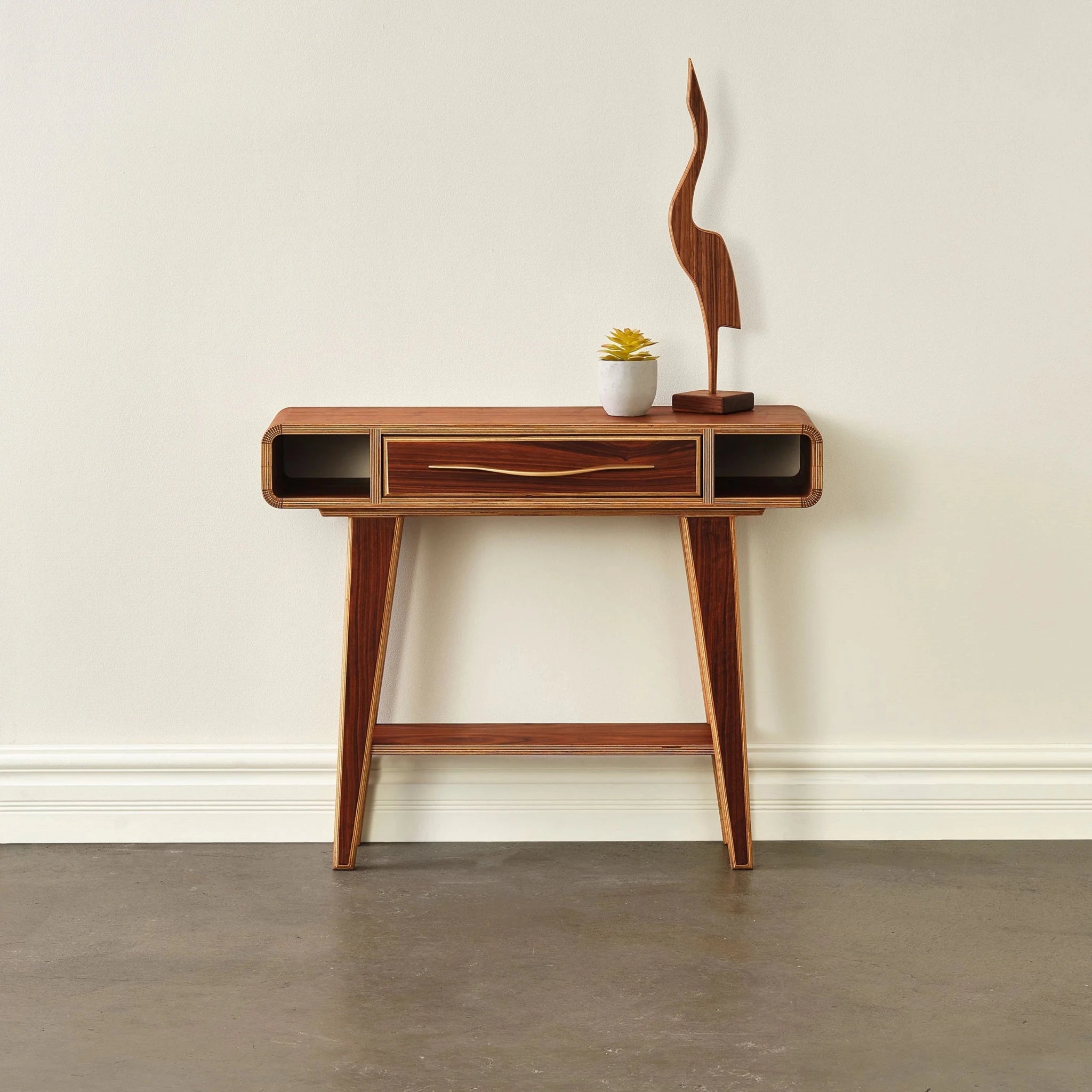 Walnut entry table, front view, styled with potted succulent and curved wood sculpture on top
