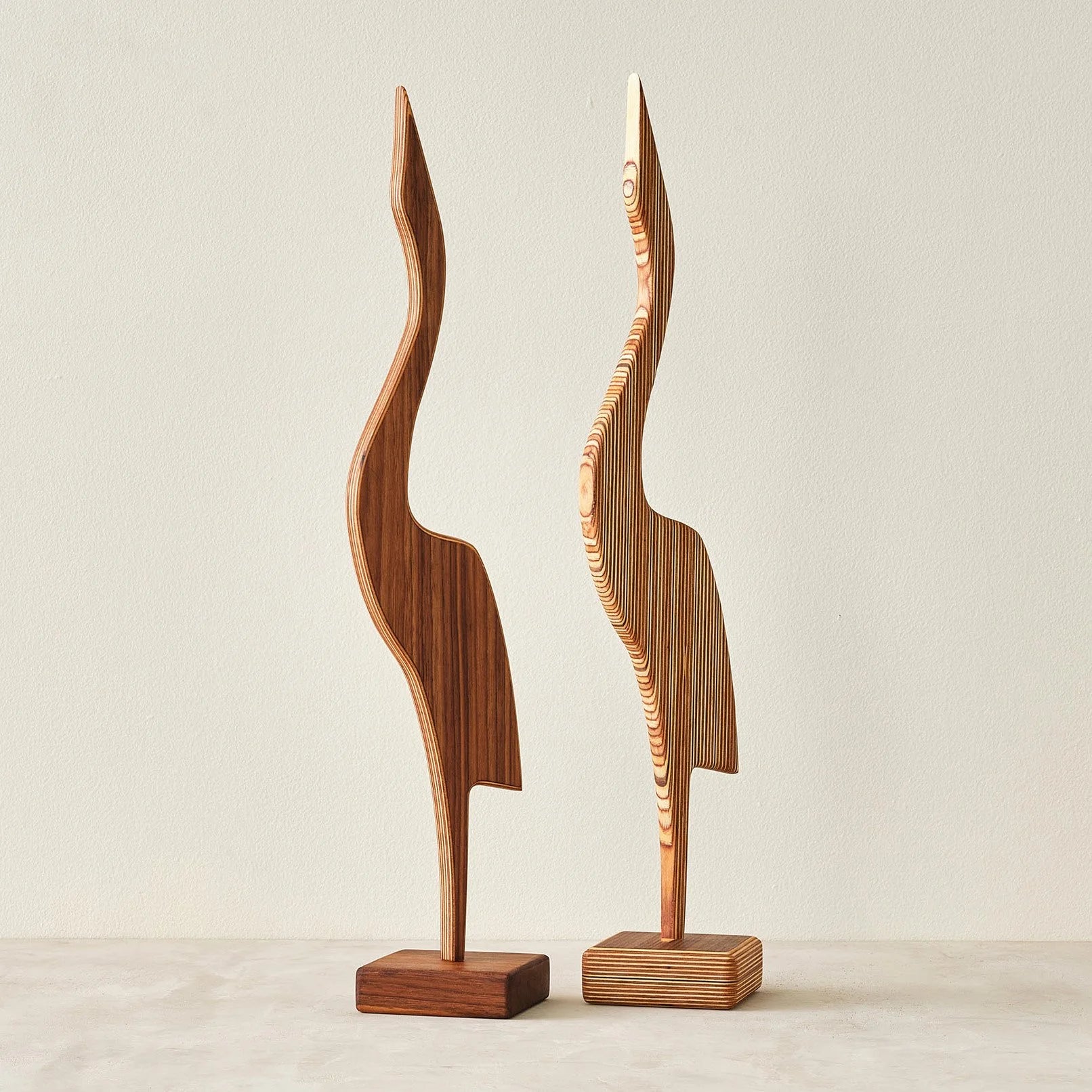 Pair of heron sculptures, walnut and layered Baltic birch, side by side on cream