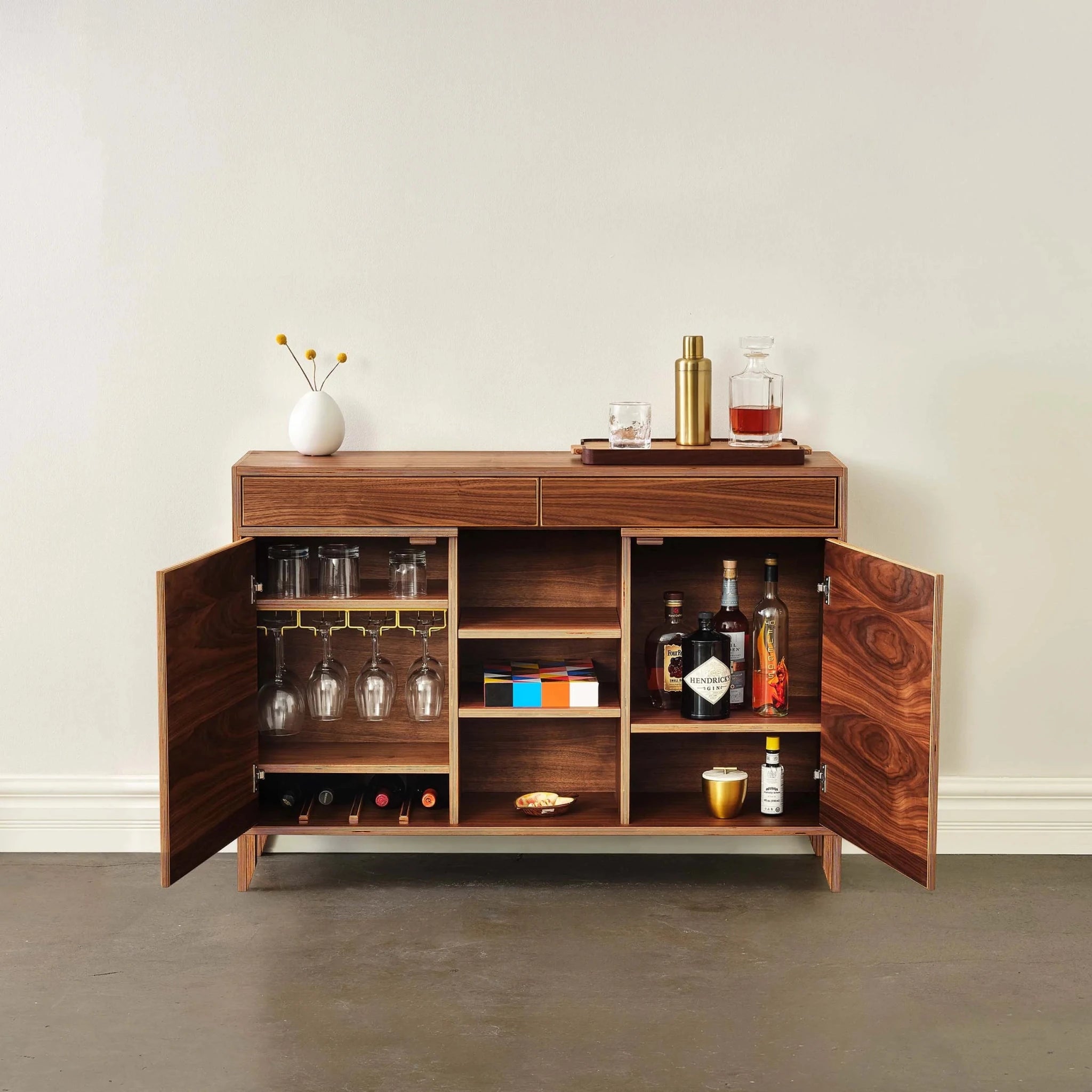Wide walnut liquor cabinet, both doors open, showing glassware, wine bottles, and shelves