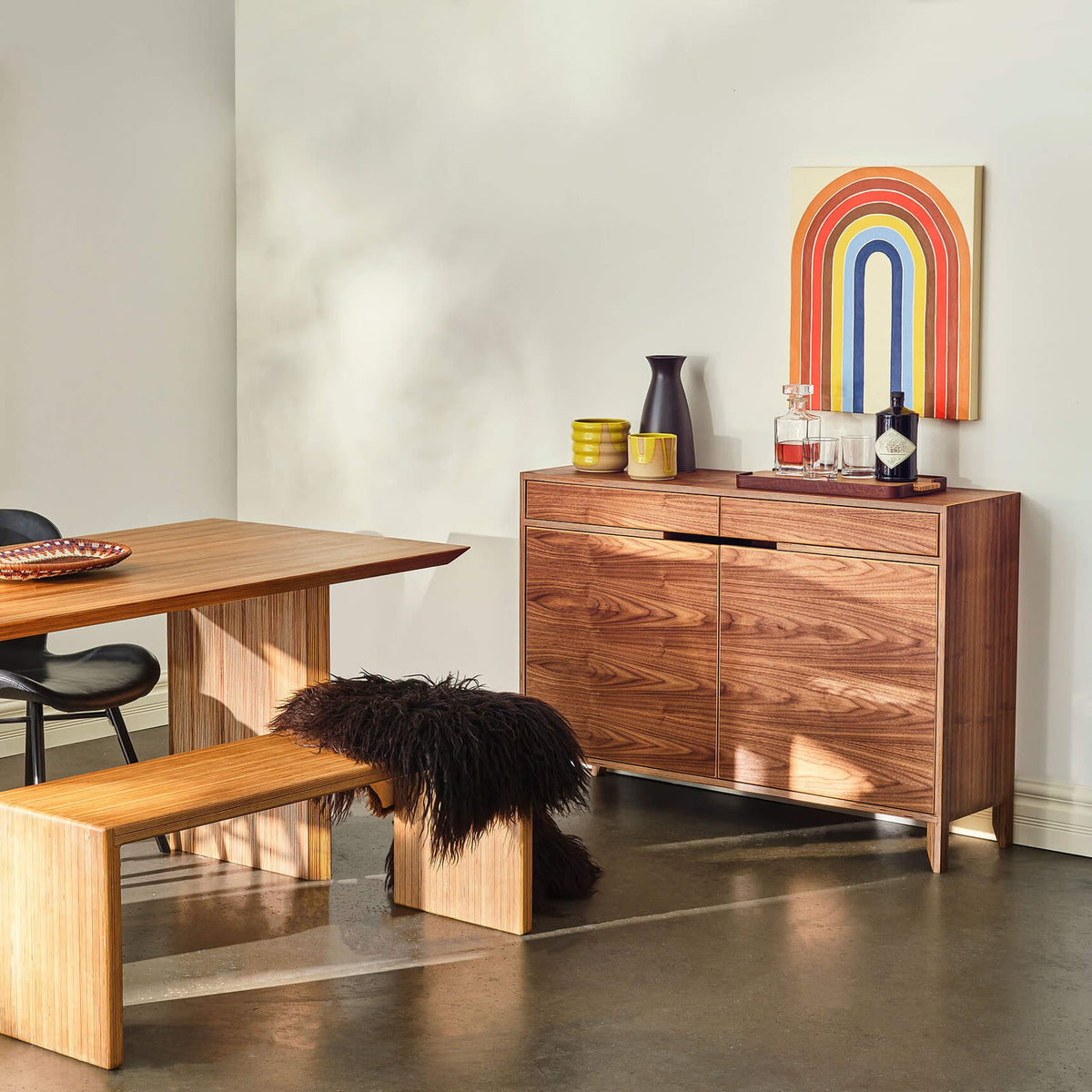 48-inch walnut liquor cabinet in styled dining room with bench and rainbow artwork
