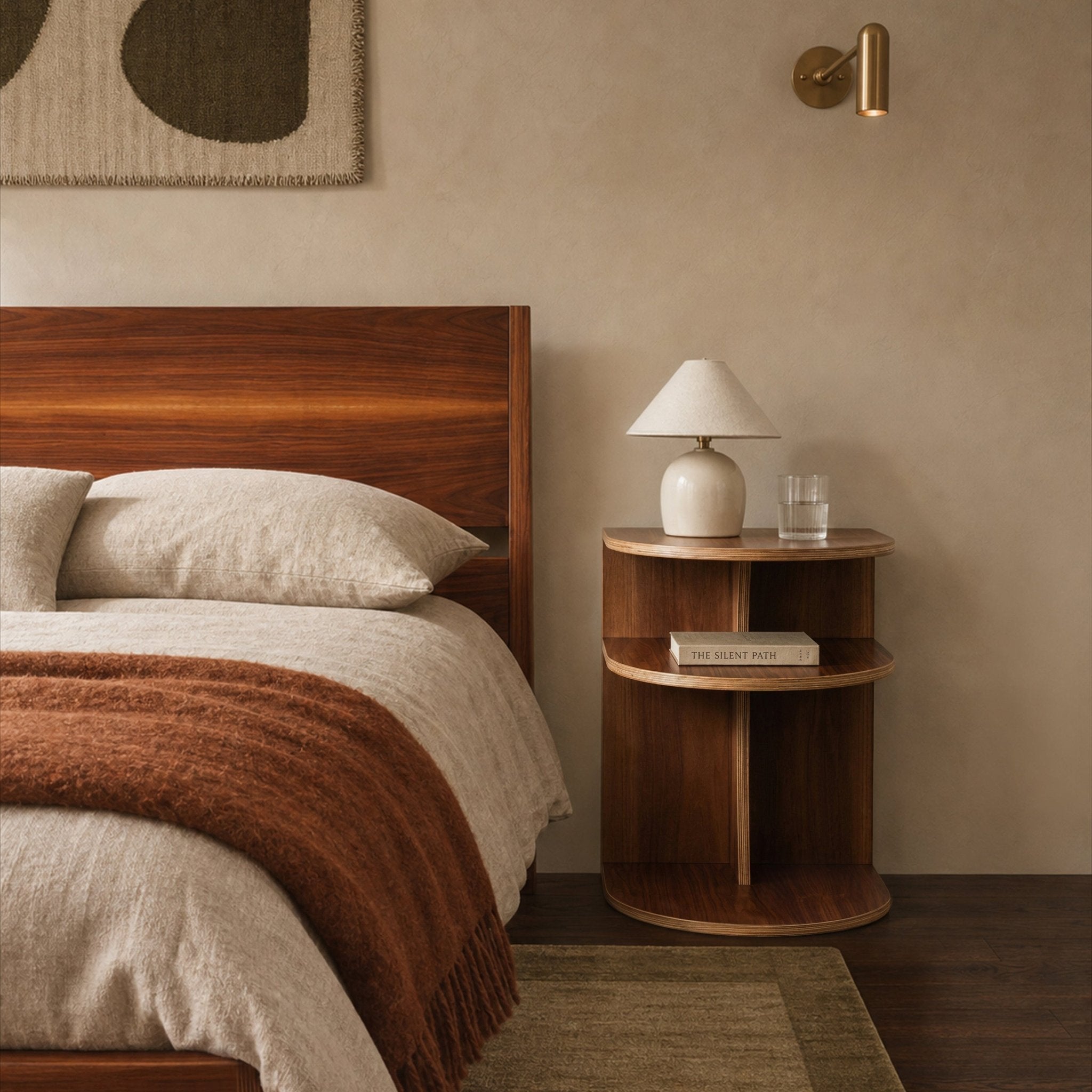 A warm, modern bedroom with a wood bed frame with beige linens, matching wood nightstand with white table lamp.