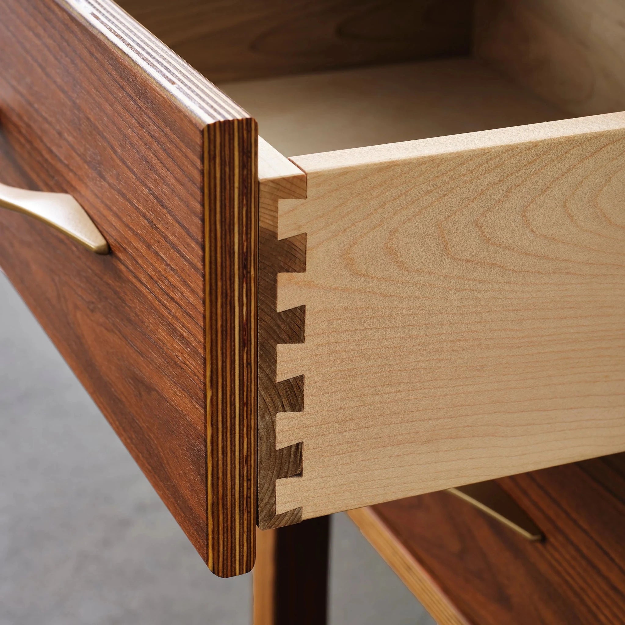 Open drawer detail showing dovetail joints, maple box, walnut front, brass pull