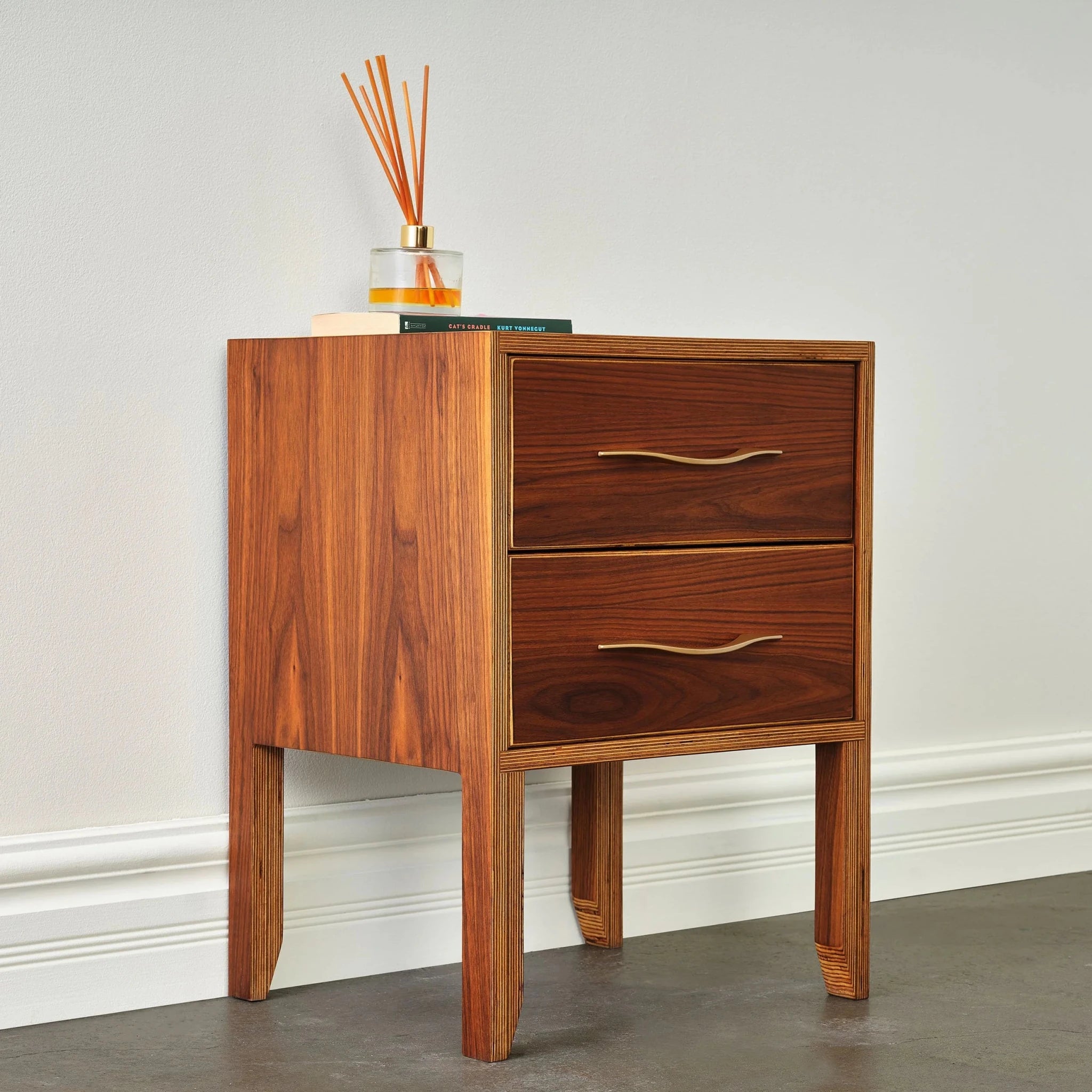Angled side view of walnut nightstand showing grain side panel and two closed drawers
