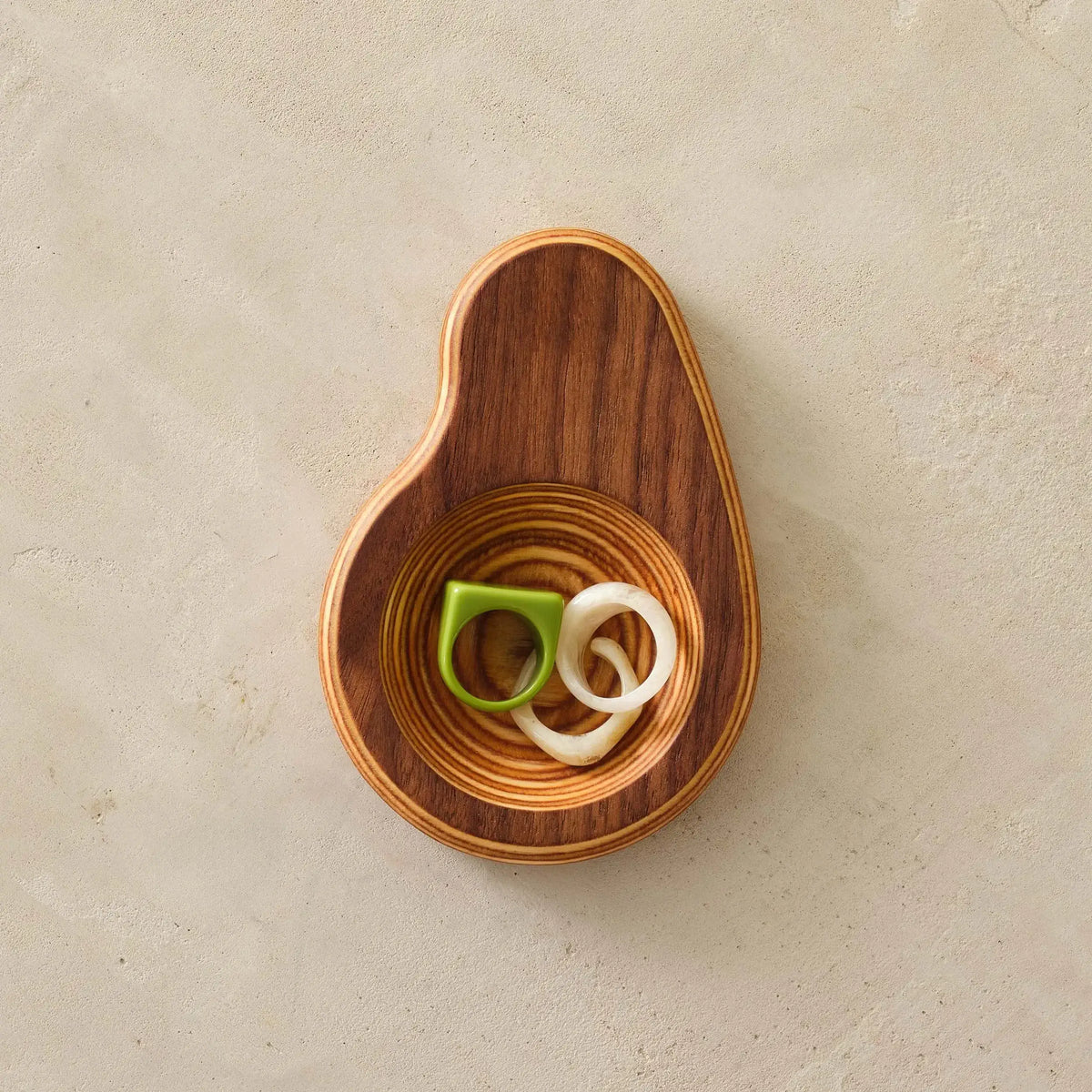 Walnut ring dish overhead holding green and white rings in birch well