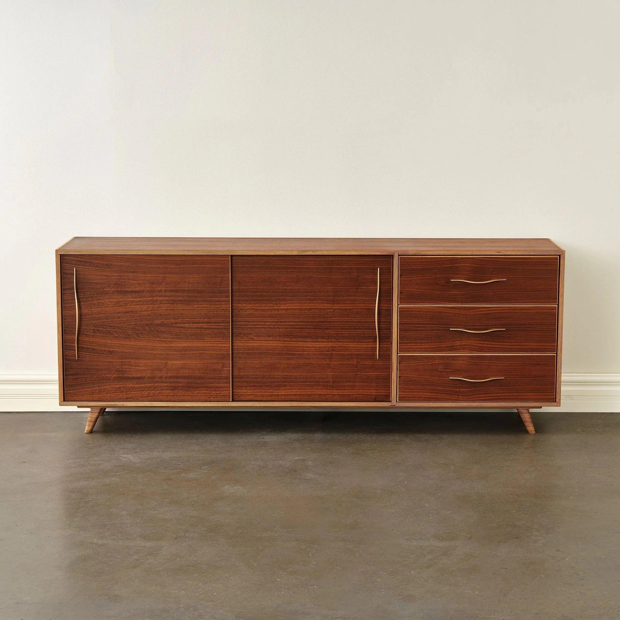 Front view of closed walnut sideboard with brass pulls on tapered legs