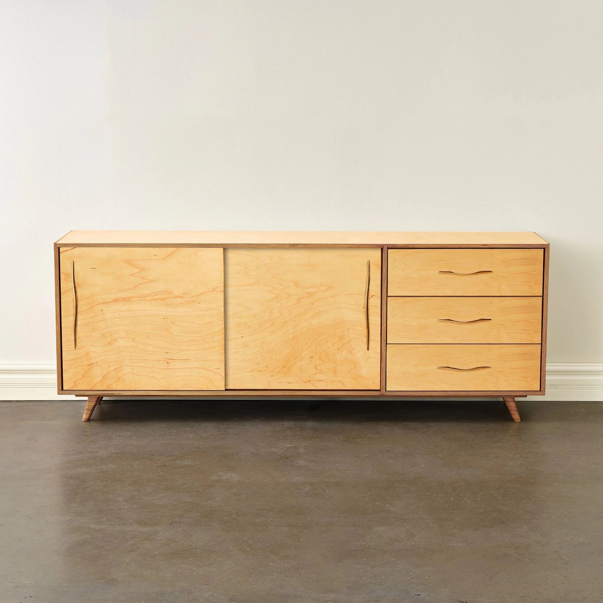 Front view of light maple sideboard, closed doors and drawers, brass handles