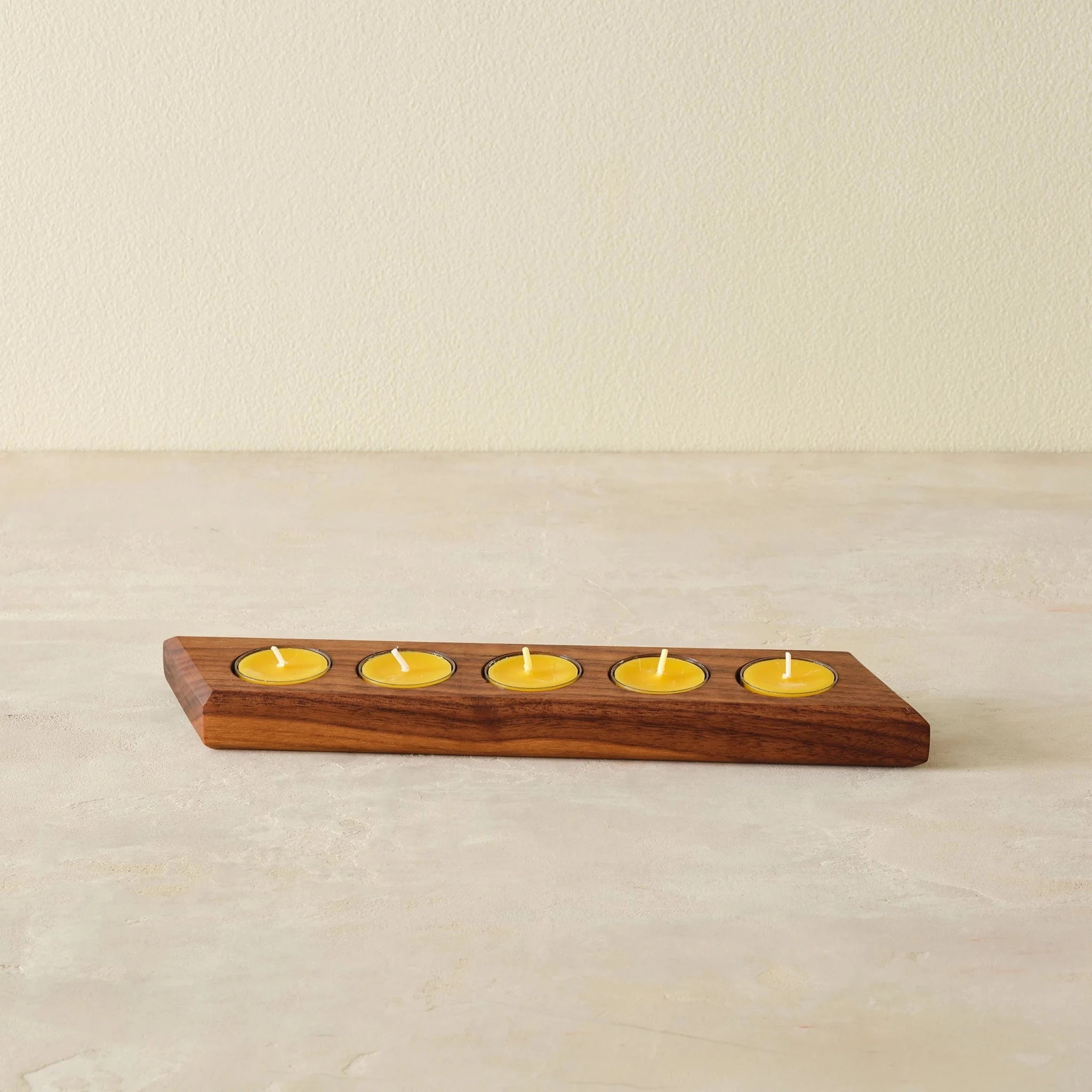 Front view walnut tealight bar holder with five yellow candles on stone