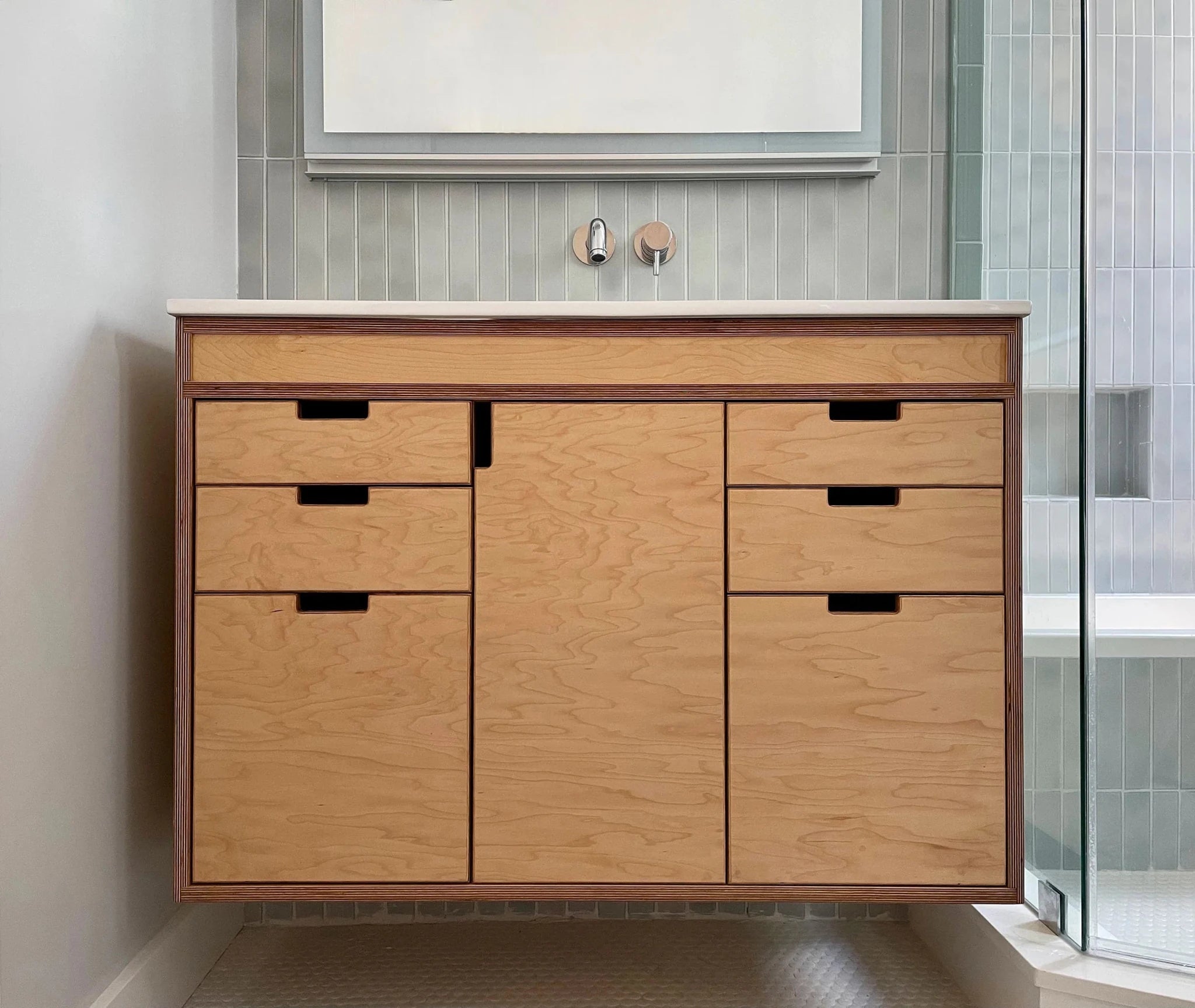 Custom maple vanity cabinet, wall-mounted, drawers and doors closed, above tiled bathroom