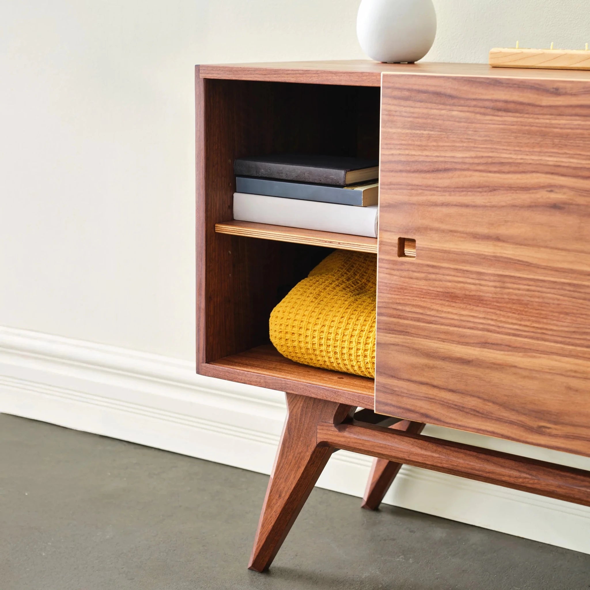 Walnut Media Console No. 2 interior, books above, yellow waffle blanket below, sliding door open