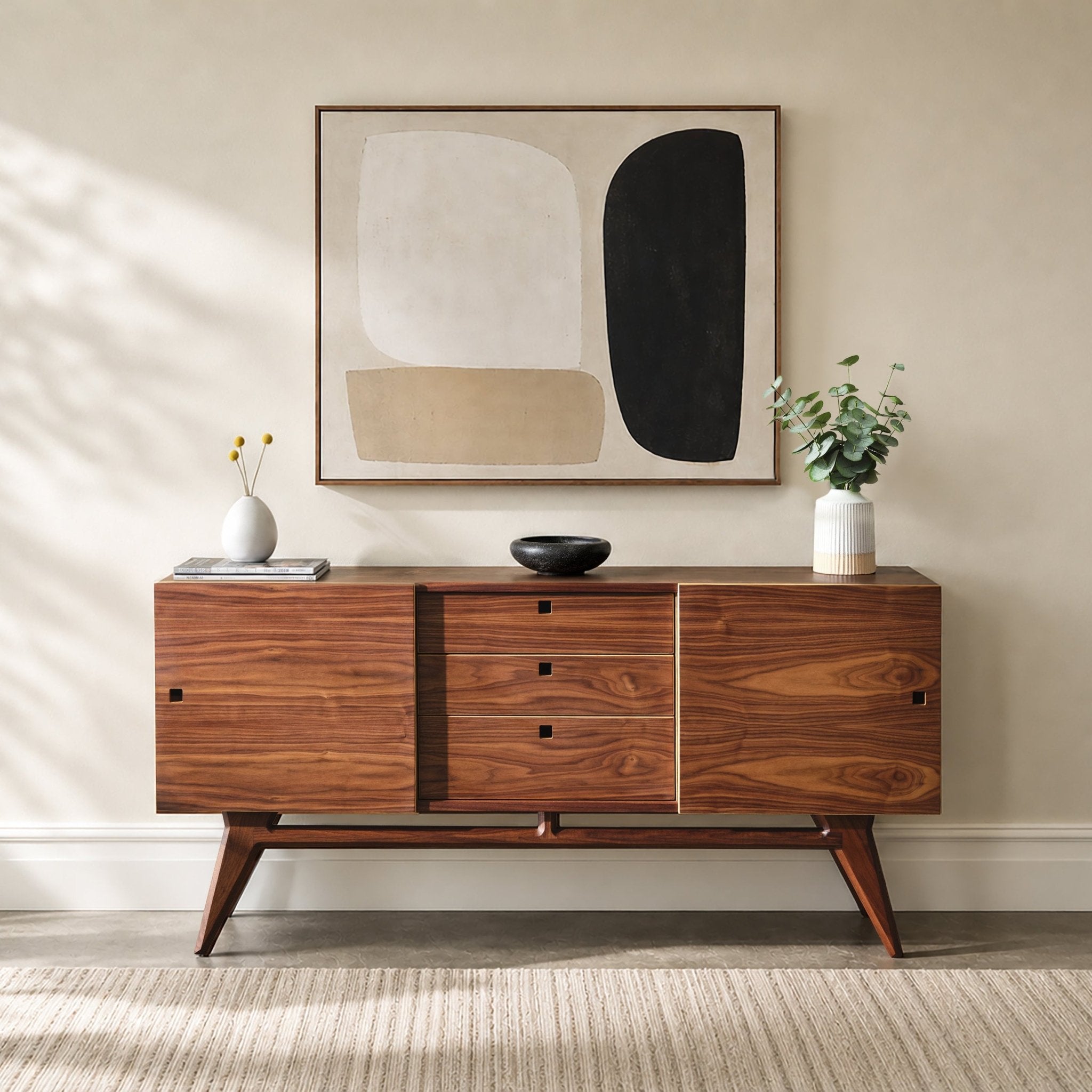 A mid-century modern wooden media console with a warm walnut finish, styled in a bright room under a framed abstract print