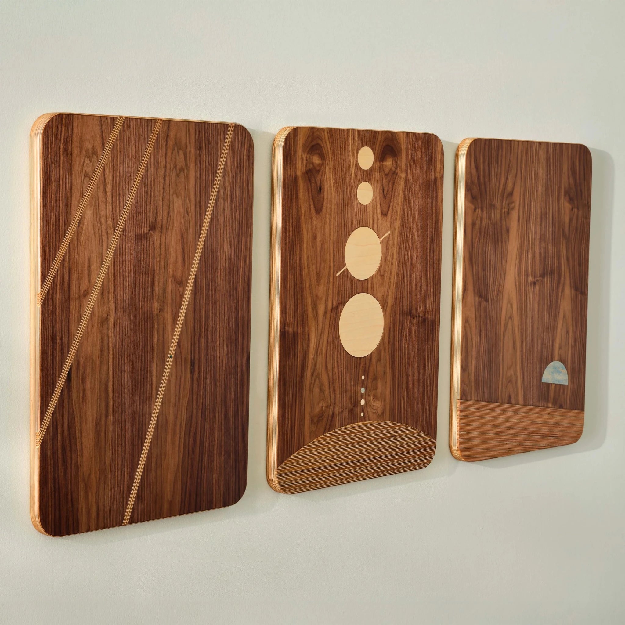 The Dot Series walnut triptych displayed at angle on wall, birch and maple inlays