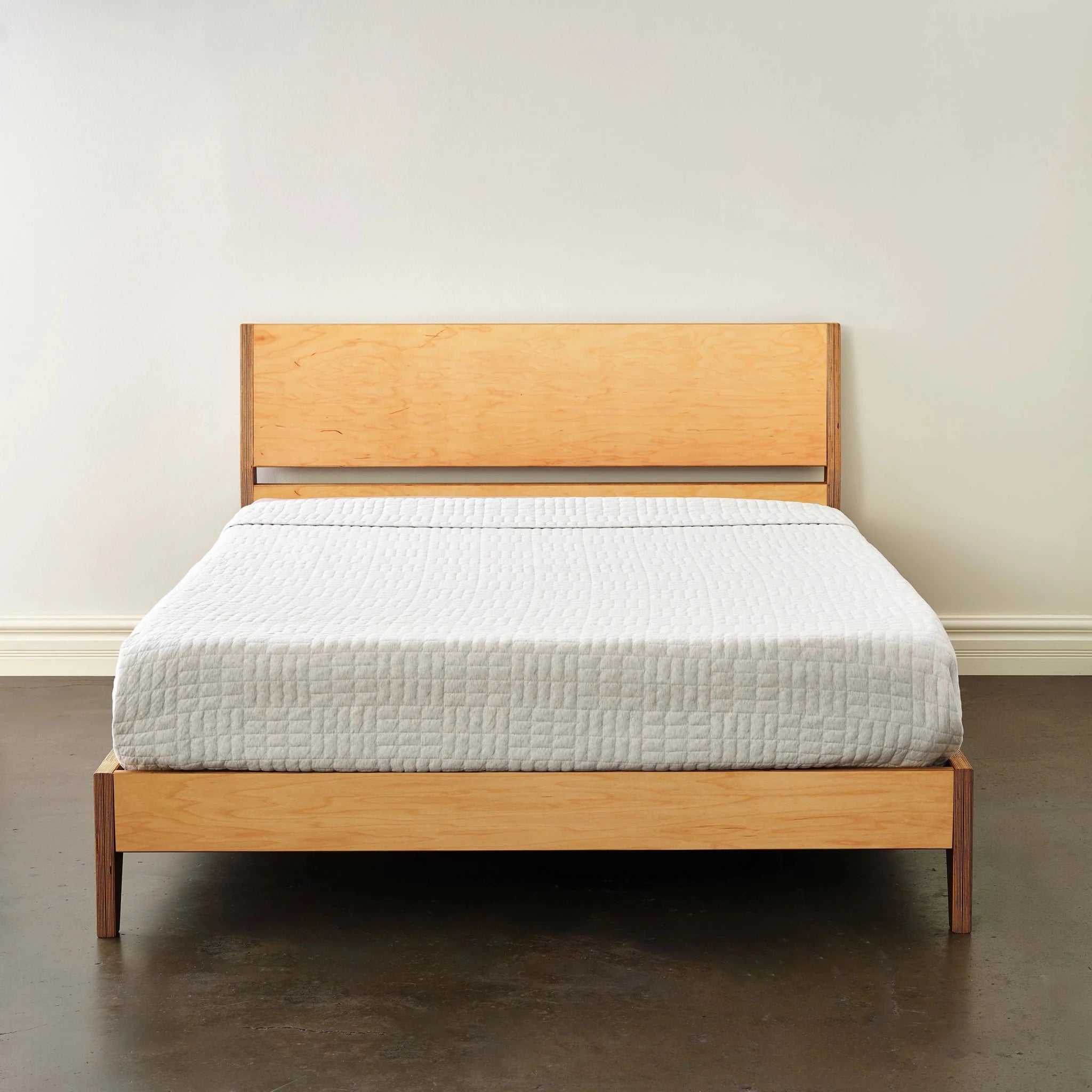 Maple platform bed with light birch headboard, front view, white quilt