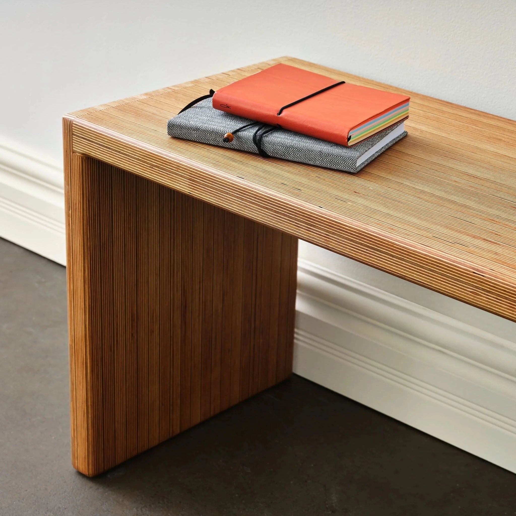 Close-up of Baltic birch bench leg, waterfall plywood edge, notebooks stacked on top