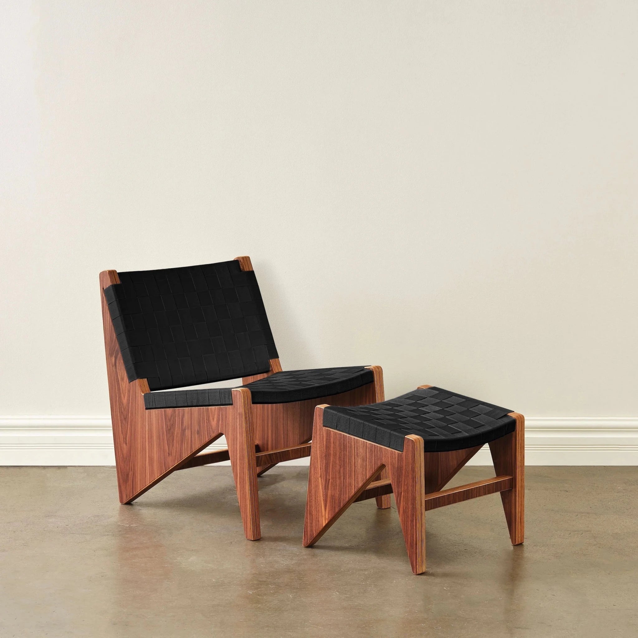 Walnut lounge chair and ottoman with black woven straps on concrete floor