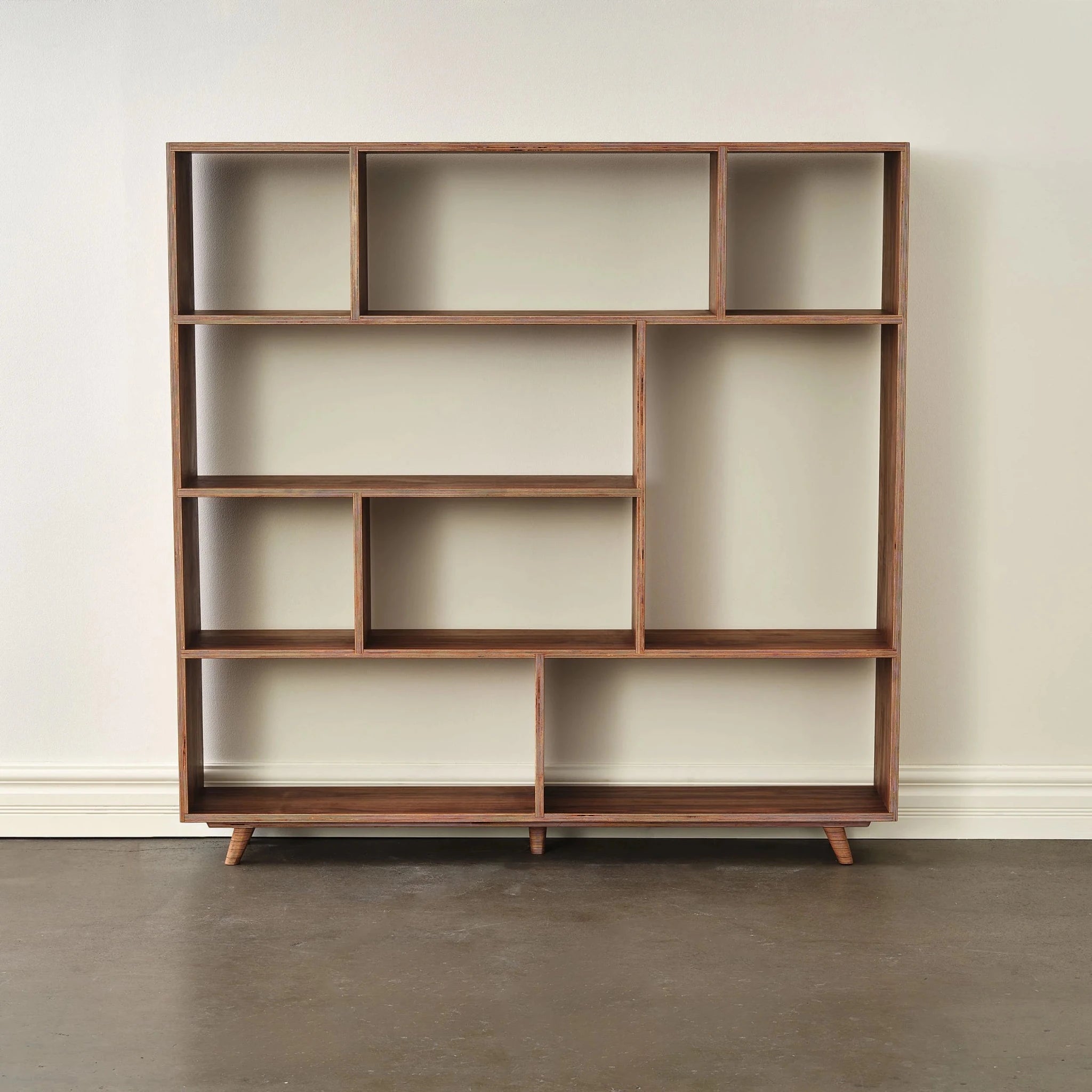 Empty walnut bookcase, wider six-shelf design, front view against white wall