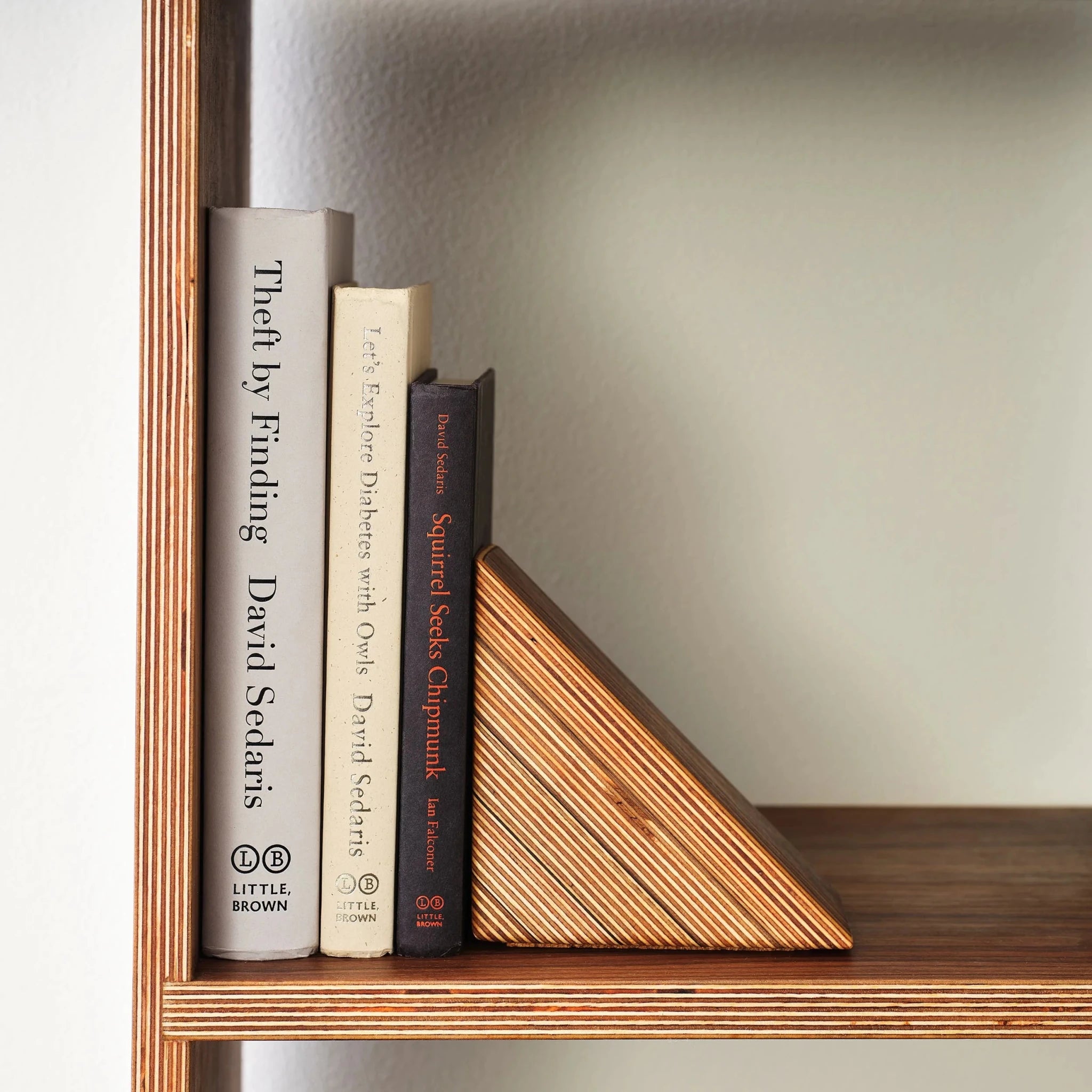 Close-up of layered birch bookend with visible plywood edges holding three books