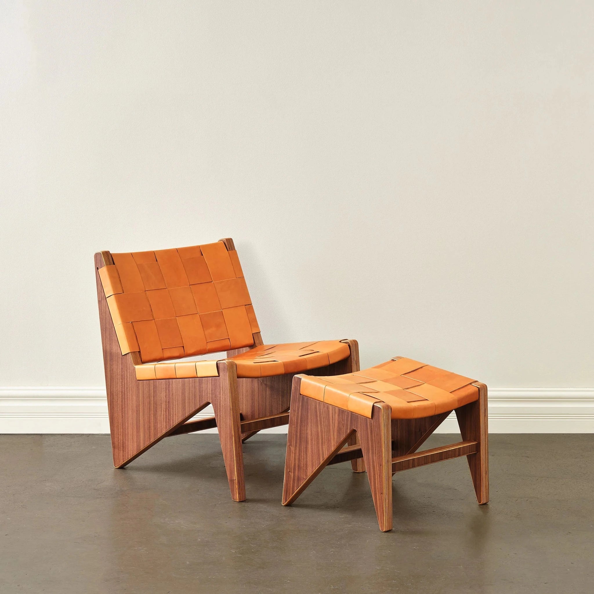 Walnut accent chair and ottoman in woven tan leather, angled staged shot, white wall