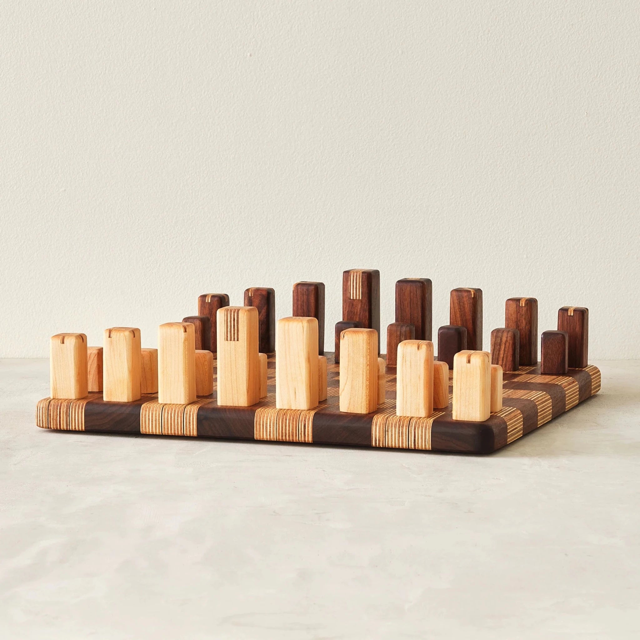 Handcrafted chess set with walnut and birch block pieces arranged on checkerboard board