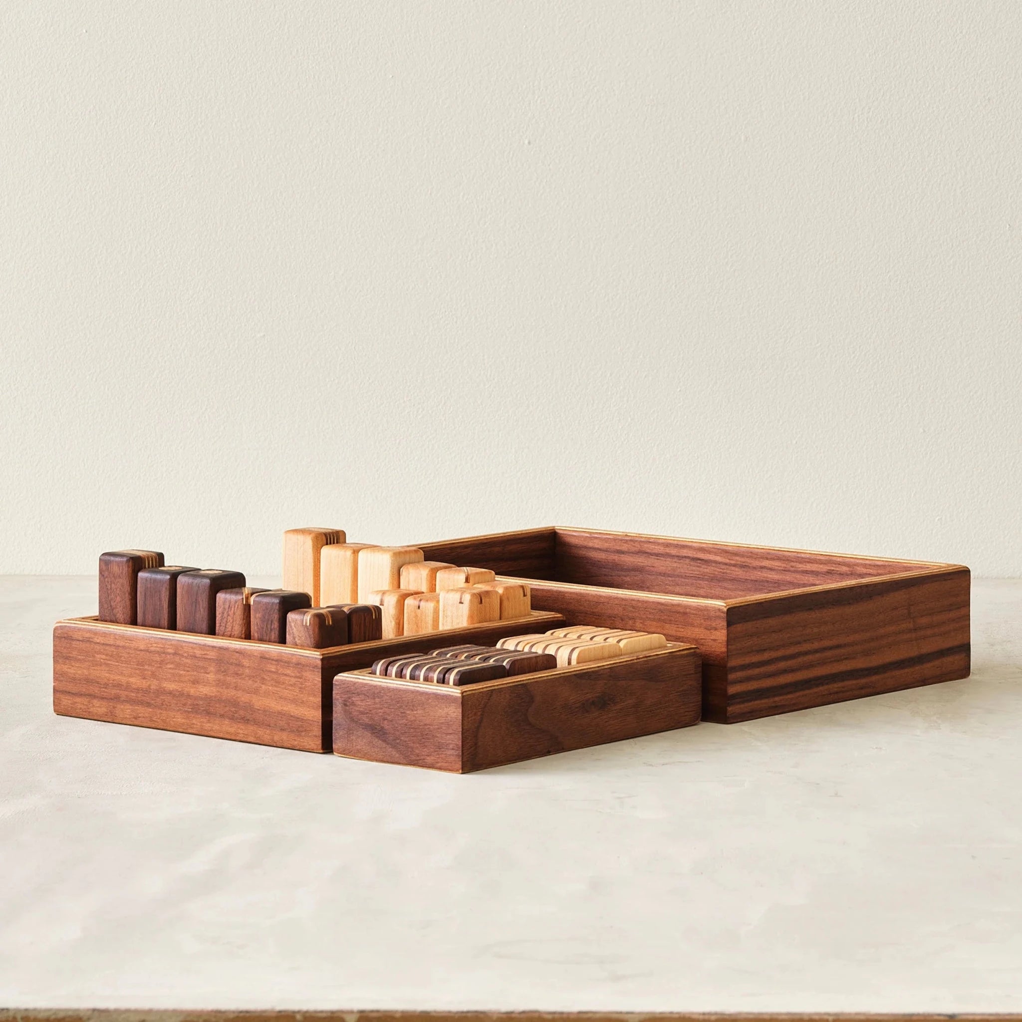 Front view of walnut storage trays holding game pieces beside empty box