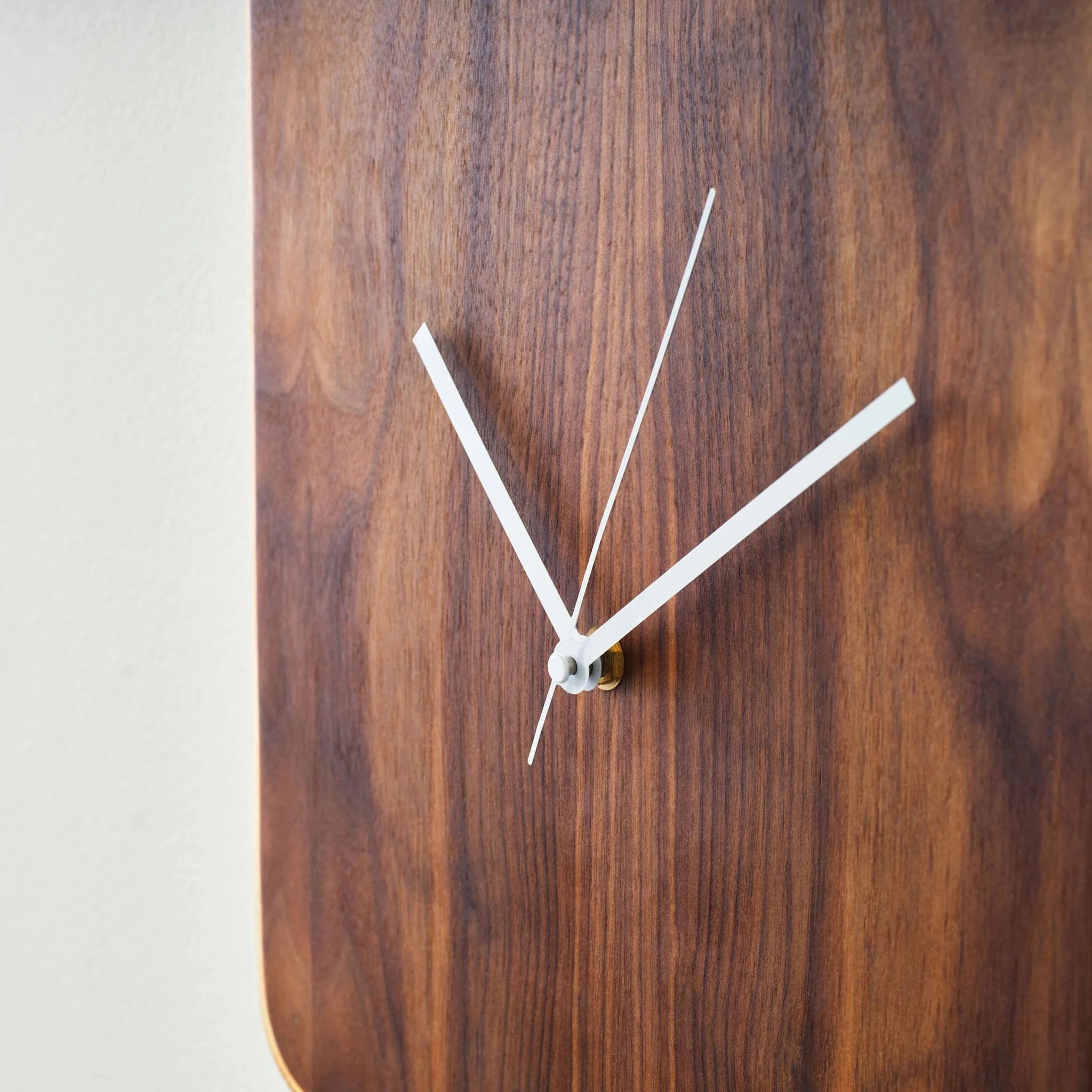 Close-up of walnut wall clock grain with white hands and brass center