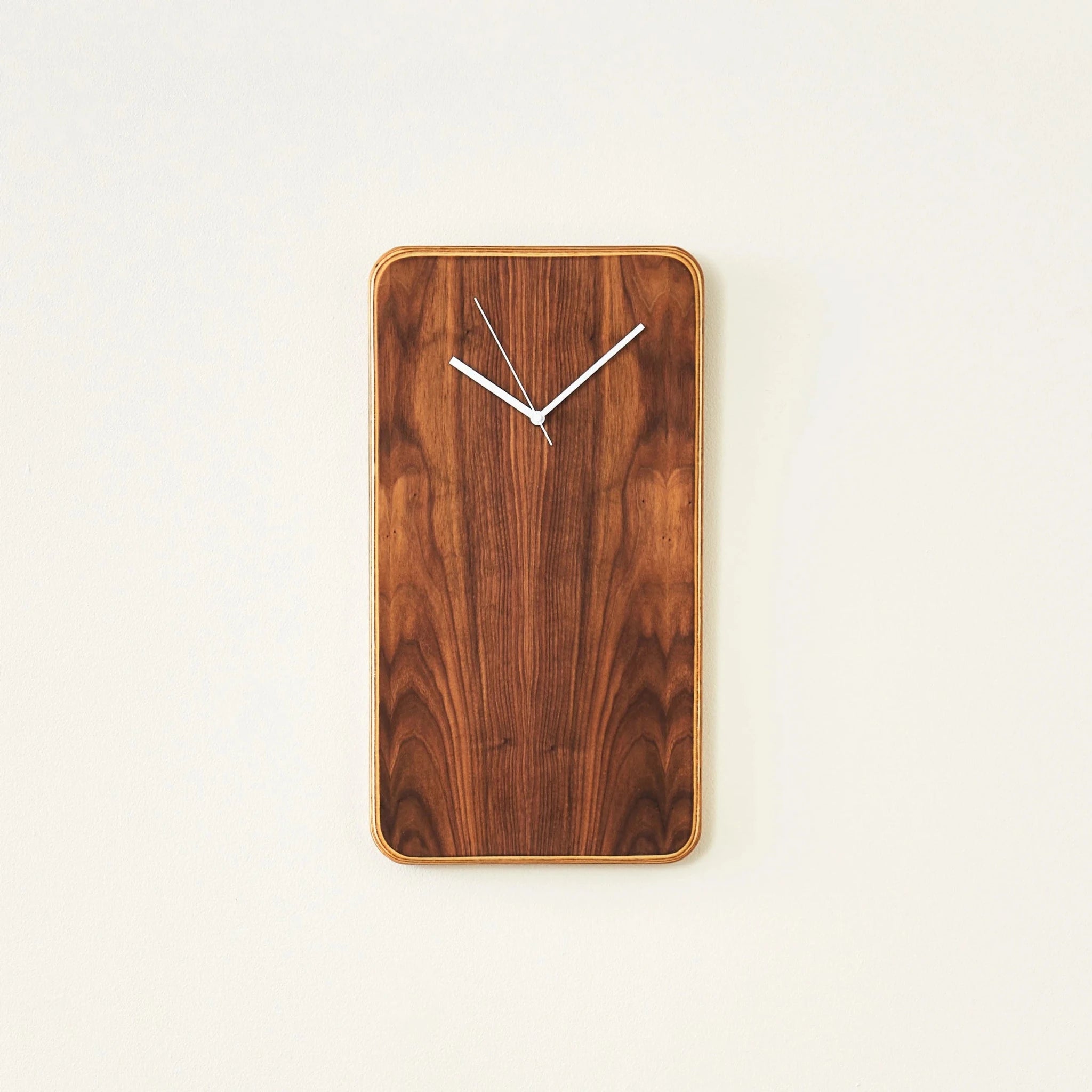 Tall vertical walnut wall clock showing symmetrical grain and white hands