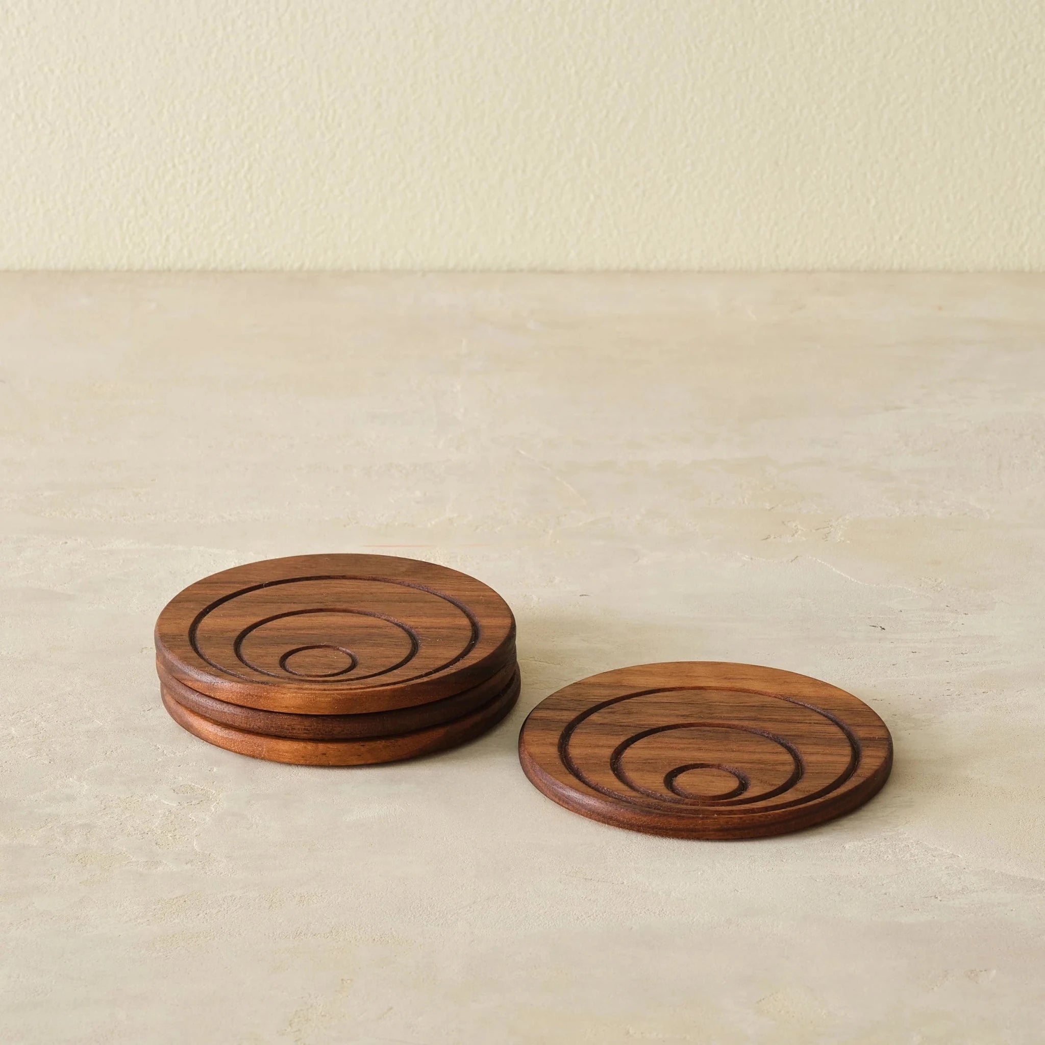 Walnut coaster set, low angle, one coaster leaning against stacked coasters