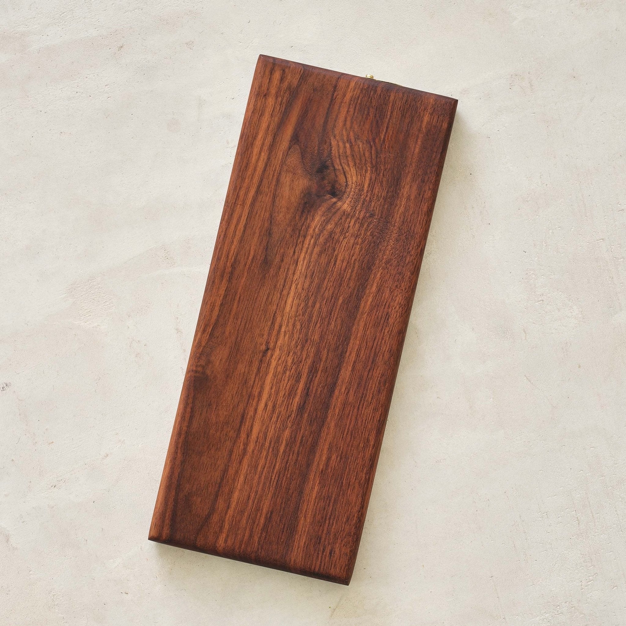 Walnut cribbage board underside showing smooth grain, on concrete surface