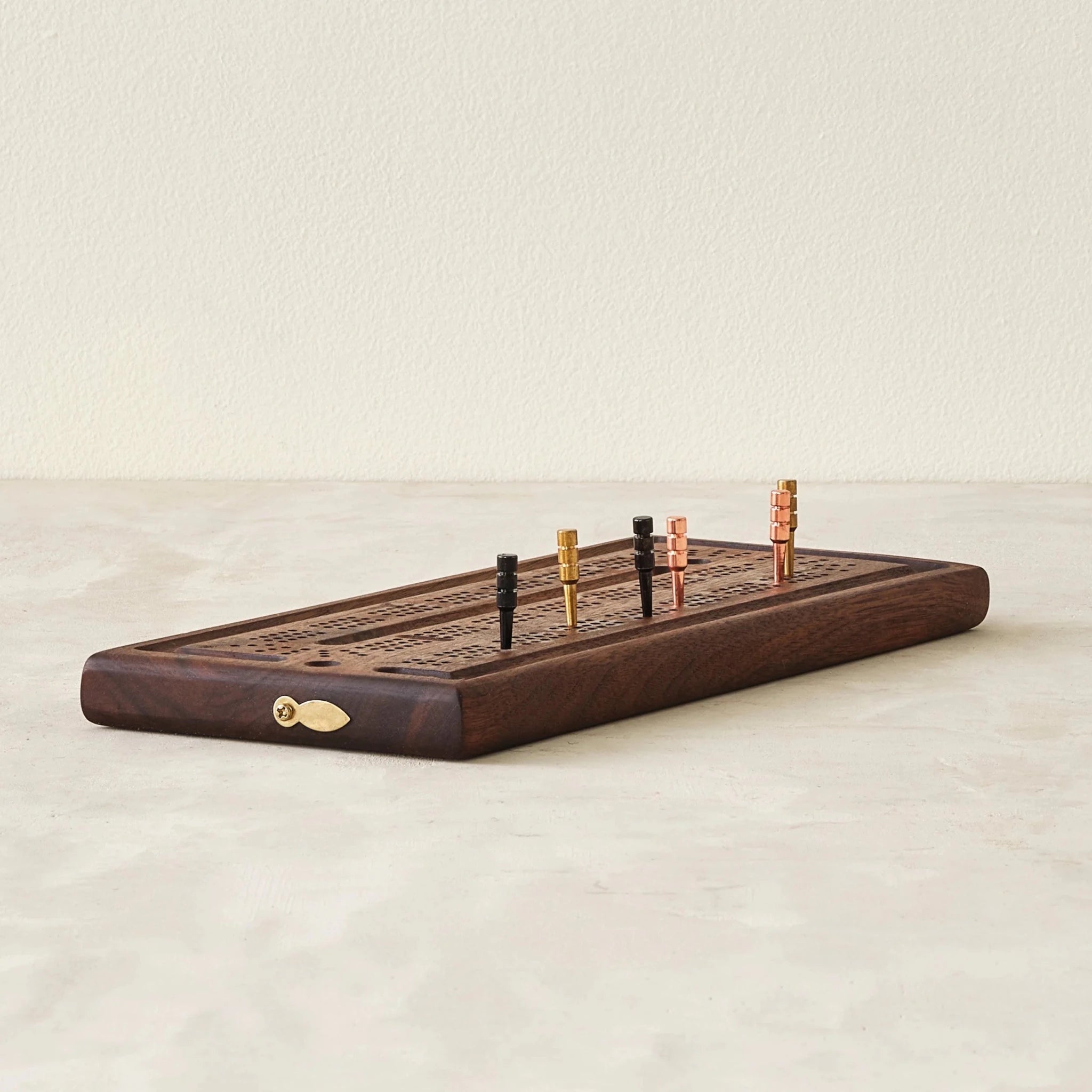 Walnut cribbage board angled front, brass copper black pegs upright in track