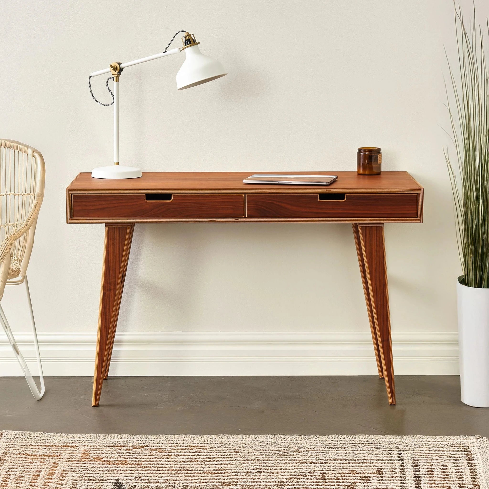 Walnut writing desk staged with white task lamp, laptop and potted plant