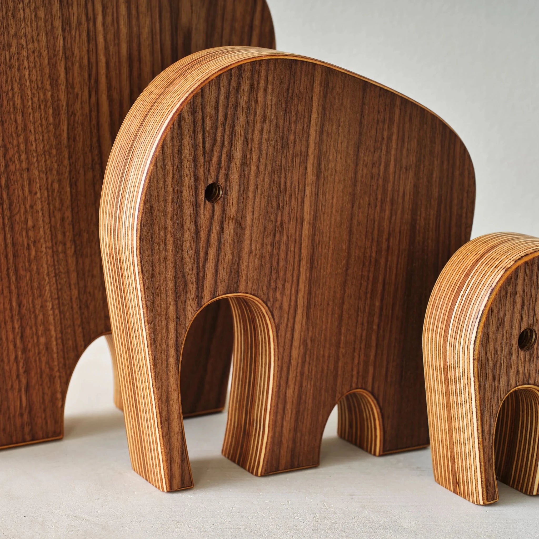 Close-up of walnut elephant sculptures showing drilled eye and layered birch edge grain