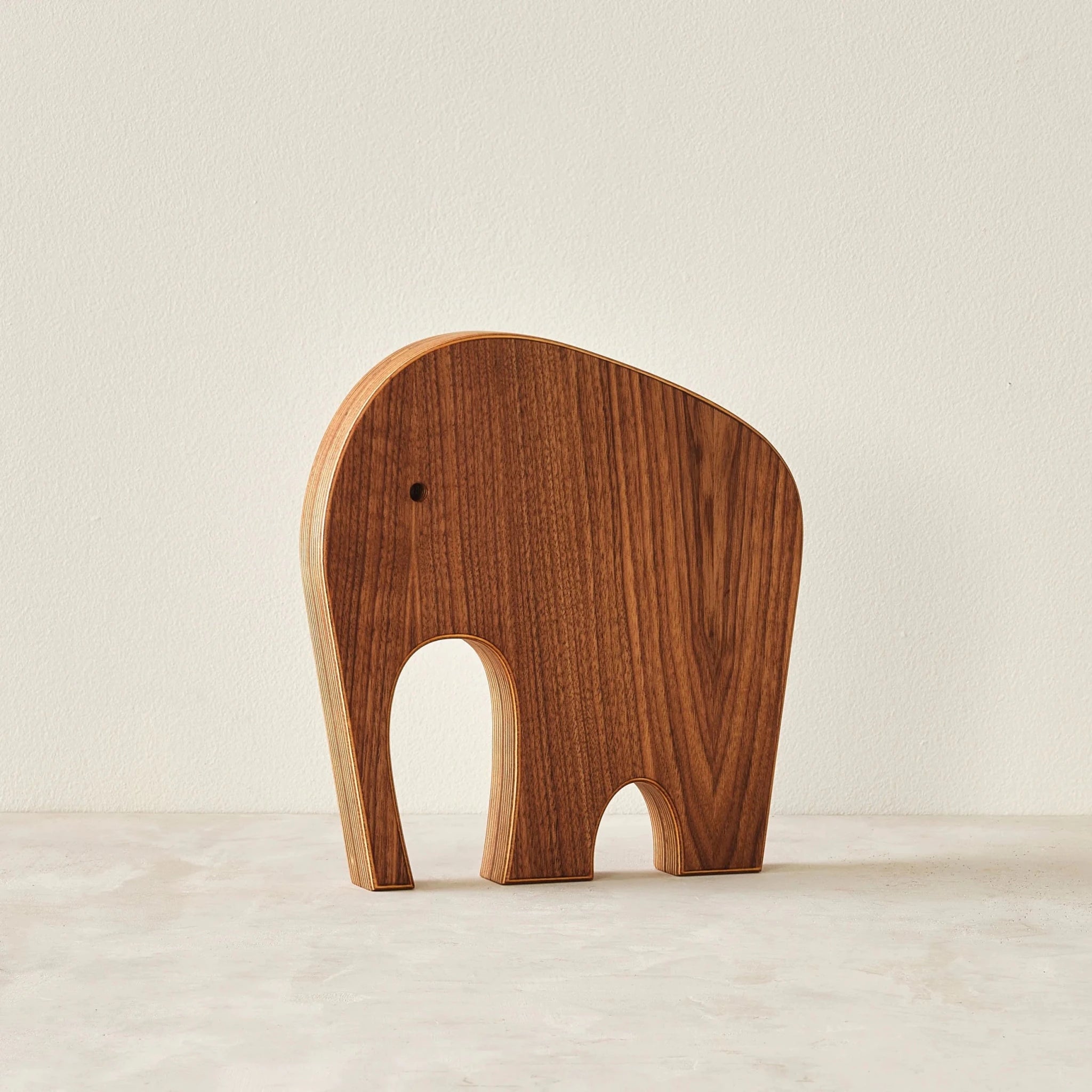 Large walnut elephant sculpture alone, front view, prominent layered birch edges, neutral background