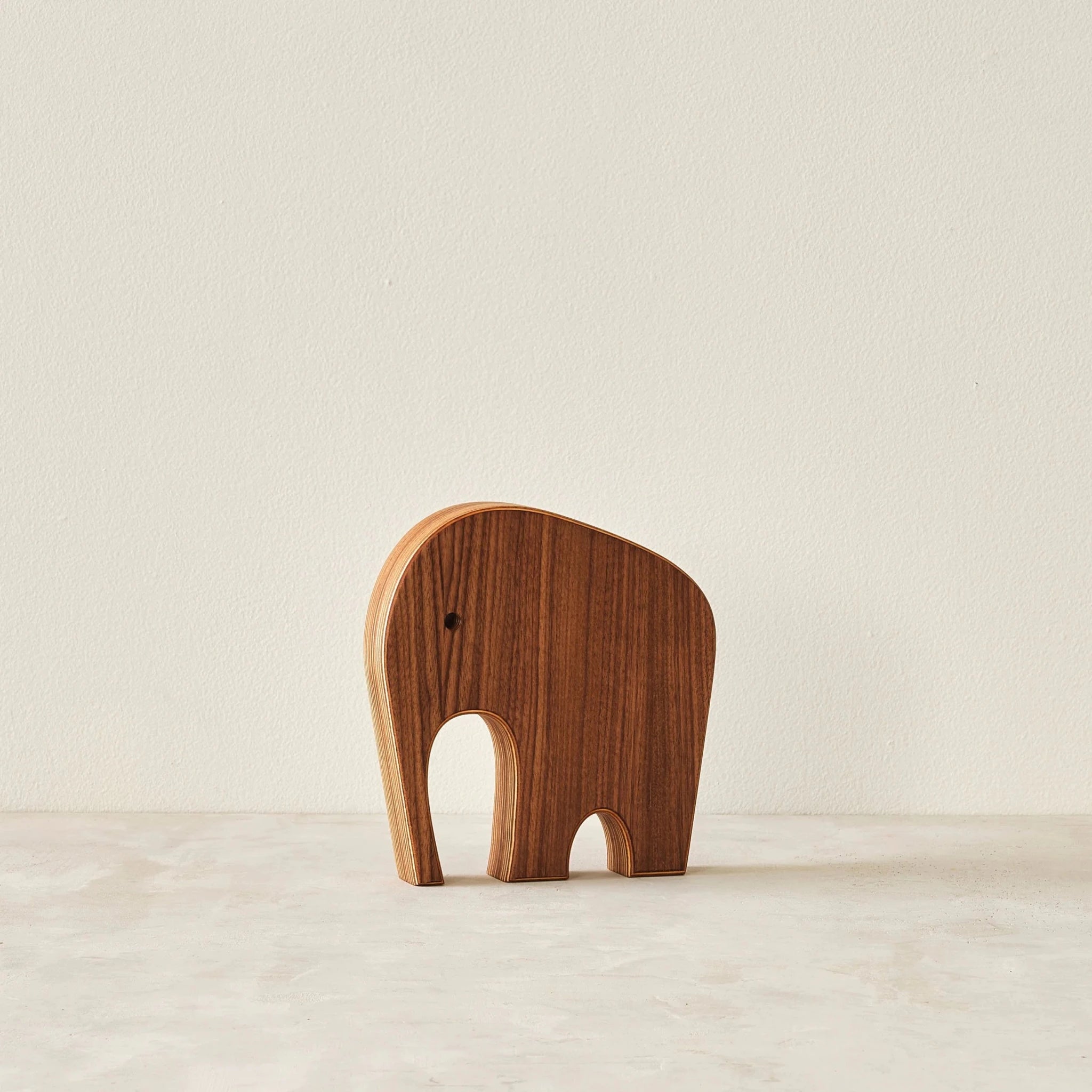 Medium walnut elephant sculpture alone, front view, layered Baltic birch edge, neutral background