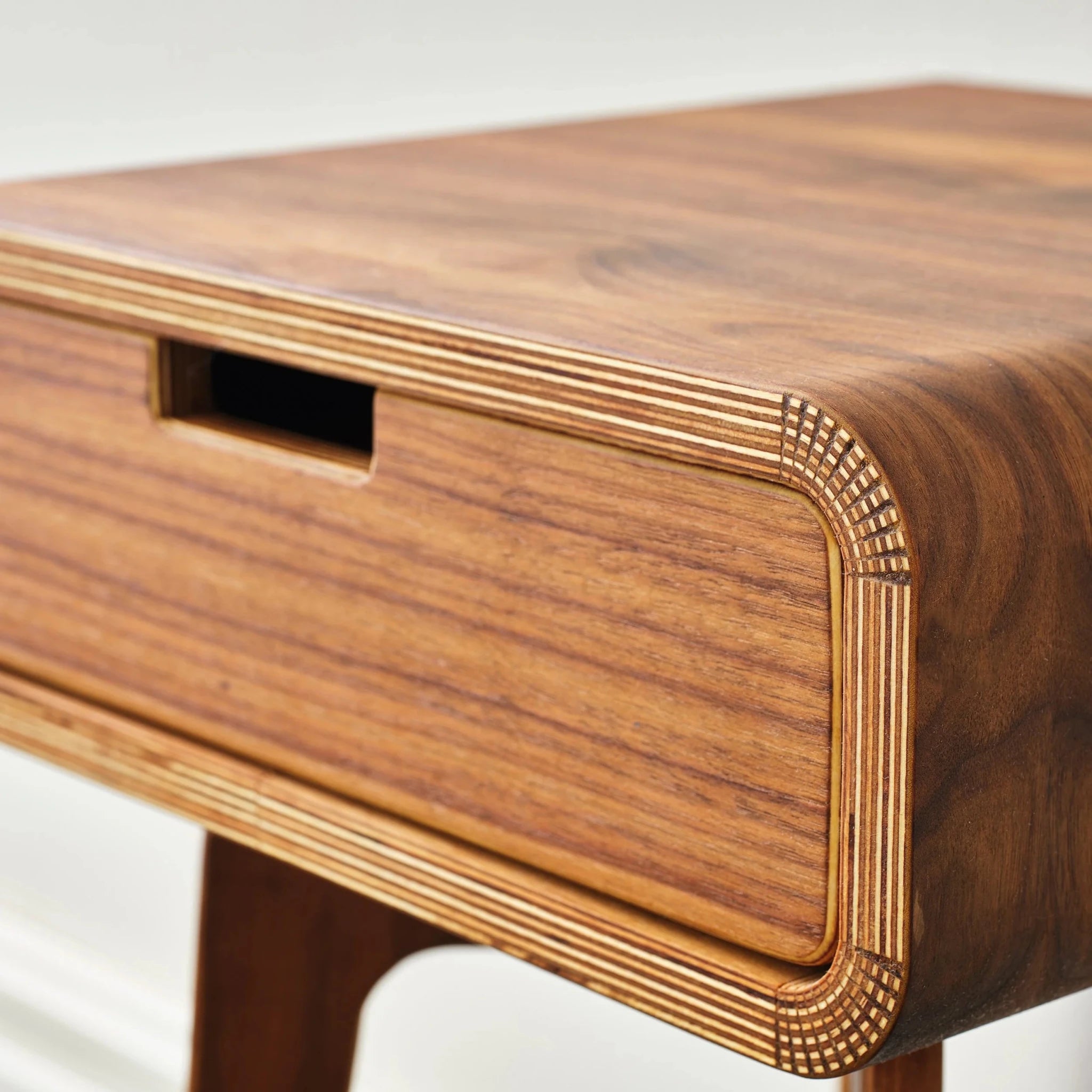 Close-up walnut end table drawer with cutout handle, exposed Baltic birch ply edge
