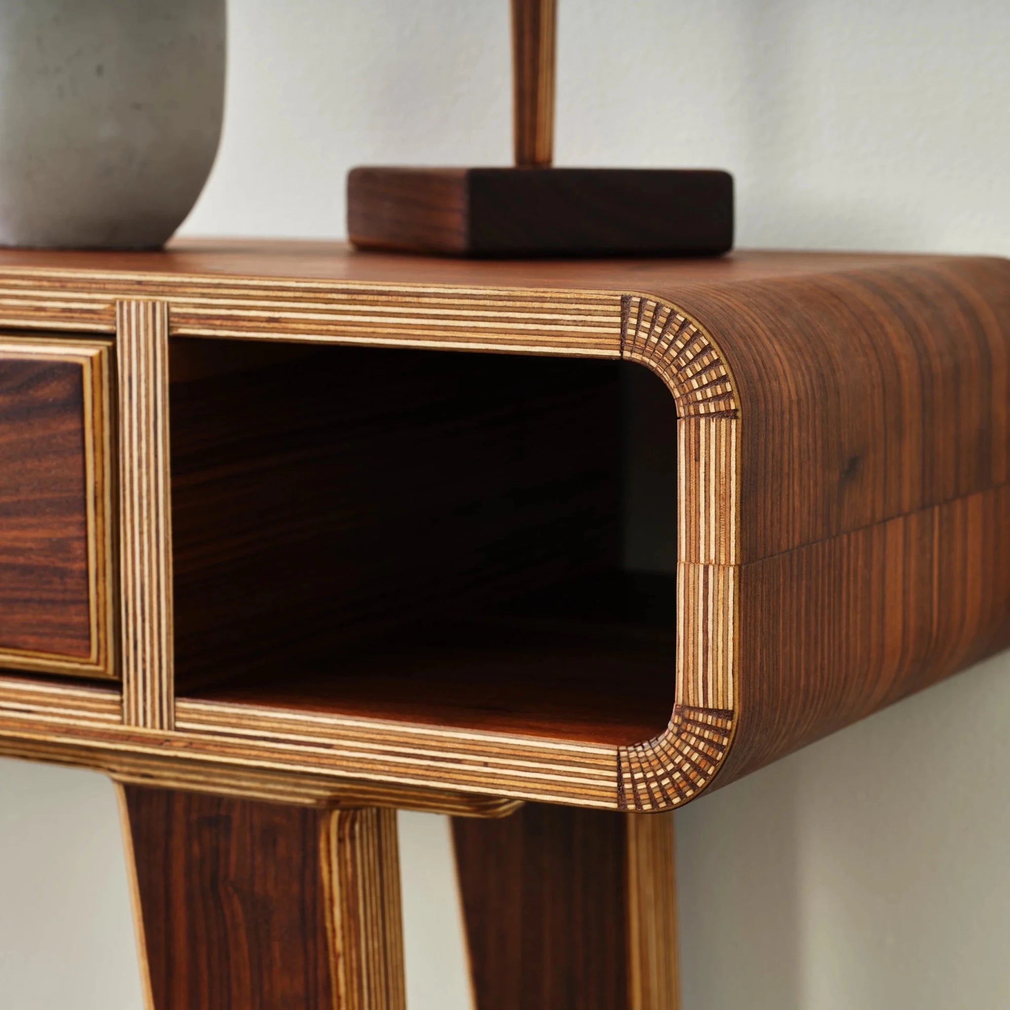 Close-up of entry table's rounded corner, exposed layered Baltic birch plywood edges, open cubby